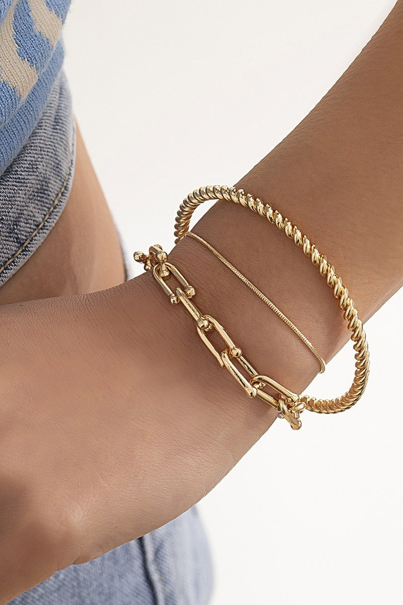 Set of three elegant gold bracelets in different shapes and sizes, showcasing unique motifs and a luxurious finish.