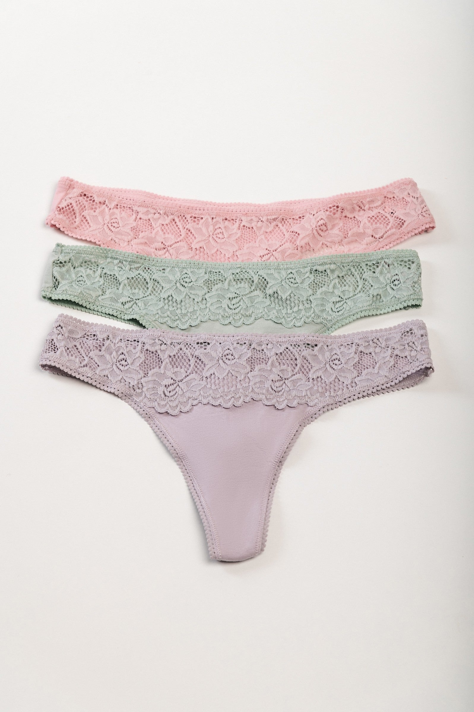 Set of three cotton thongs with lace in grey, light pink, and light green colors, showcasing their elegant design and comfortable fit.