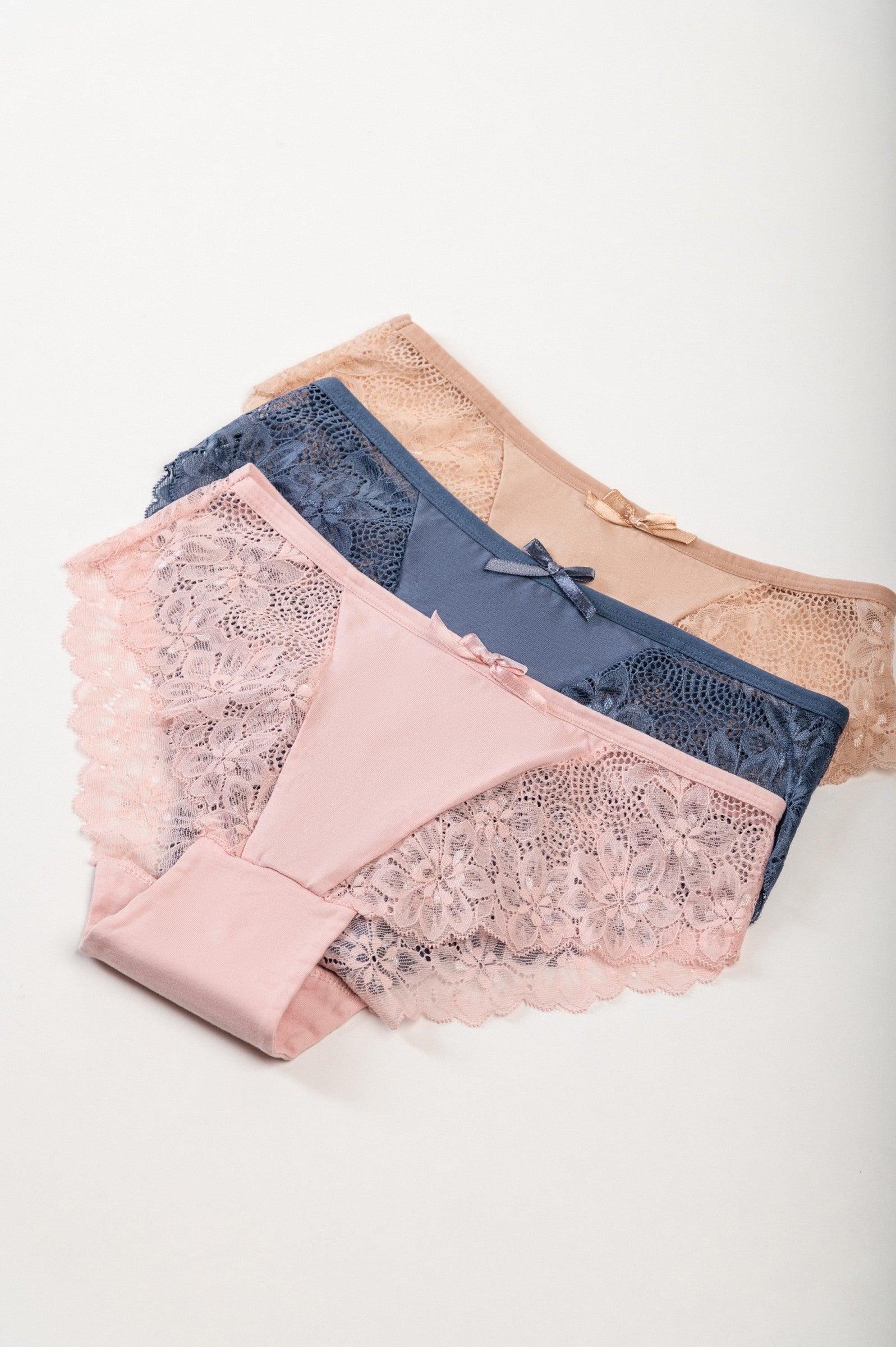 Set of three lace panties in blue, pink, and beige, showcasing delicate lace detailing and high-quality elastic fabric.