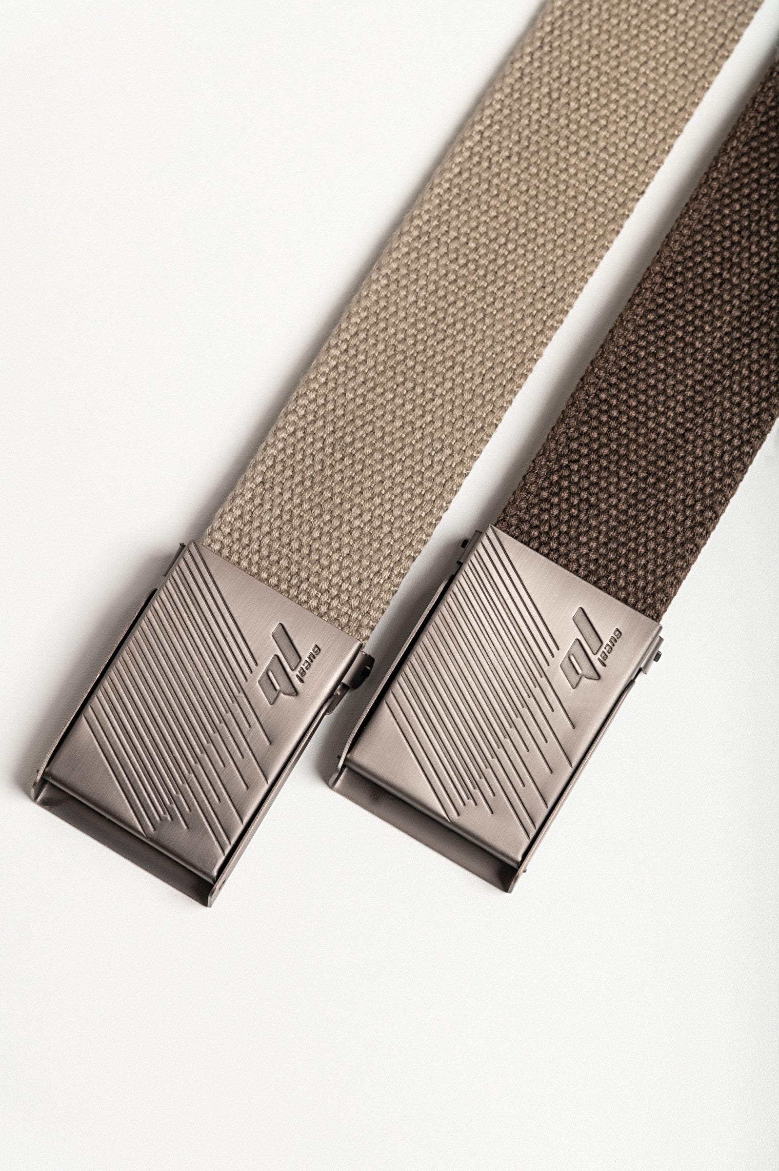 Set of two stylish trouser belts in brown and beige with metal buckles featuring elegant engravings.