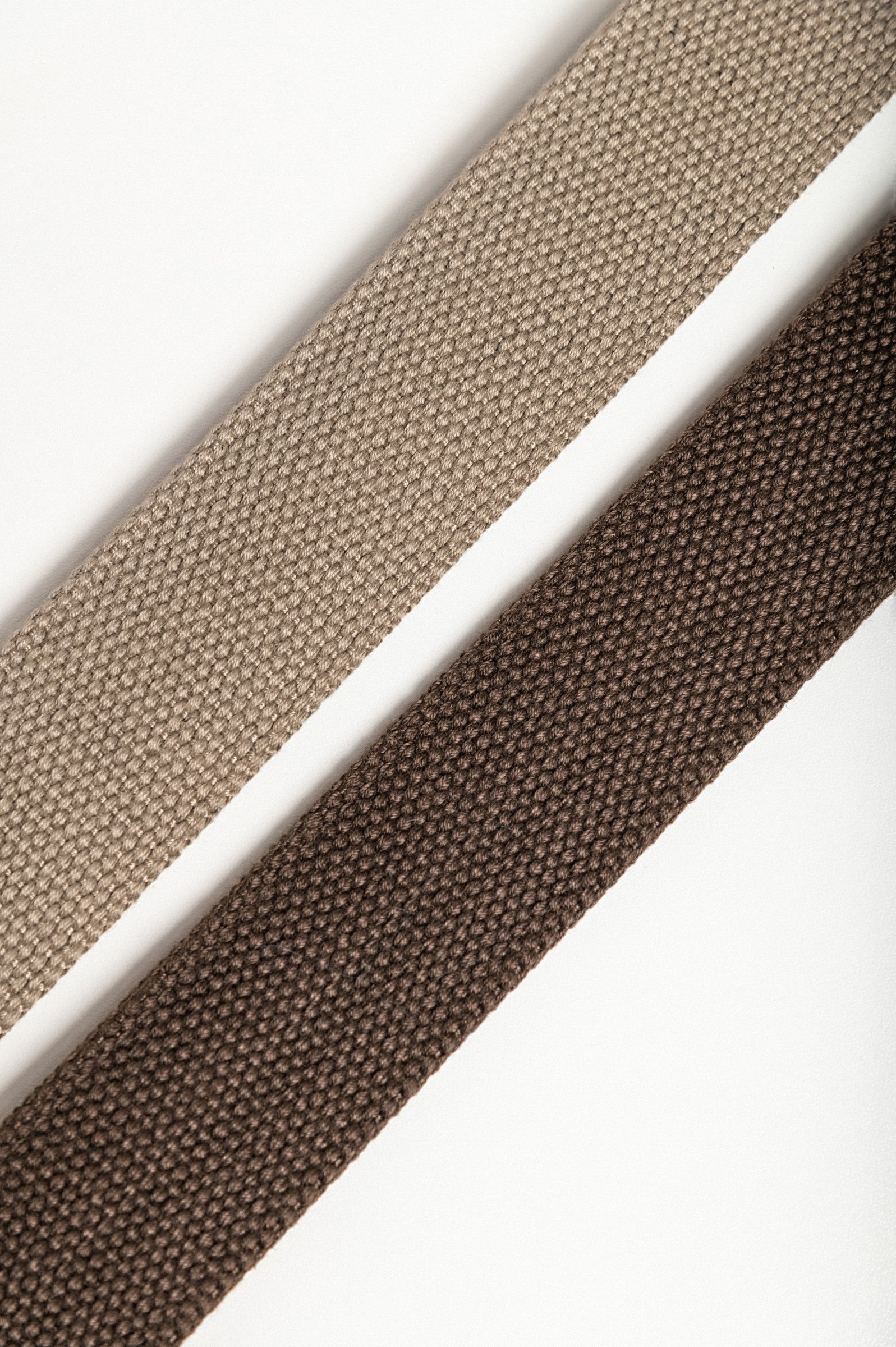 Set of two stylish trouser belts in brown and beige with metal buckles featuring elegant engravings.