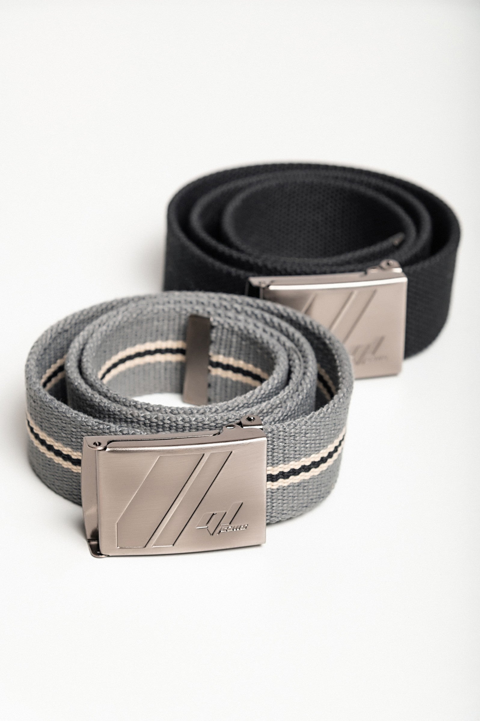 Set of two adjustable belts in black and gray with engraved metal buckles.