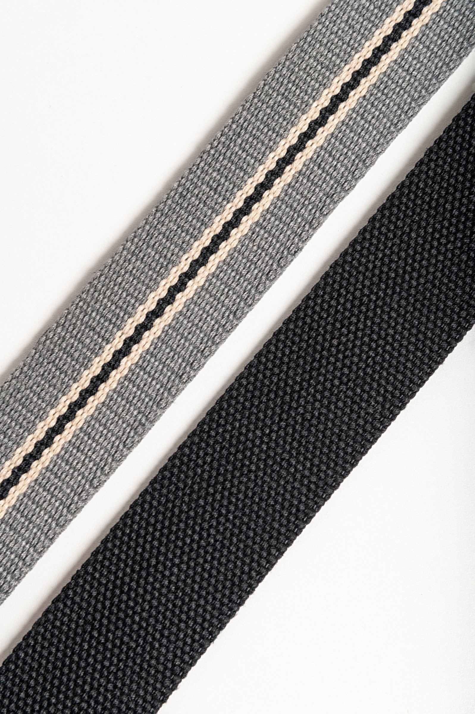 Set of two adjustable belts in black and gray with engraved metal buckles.