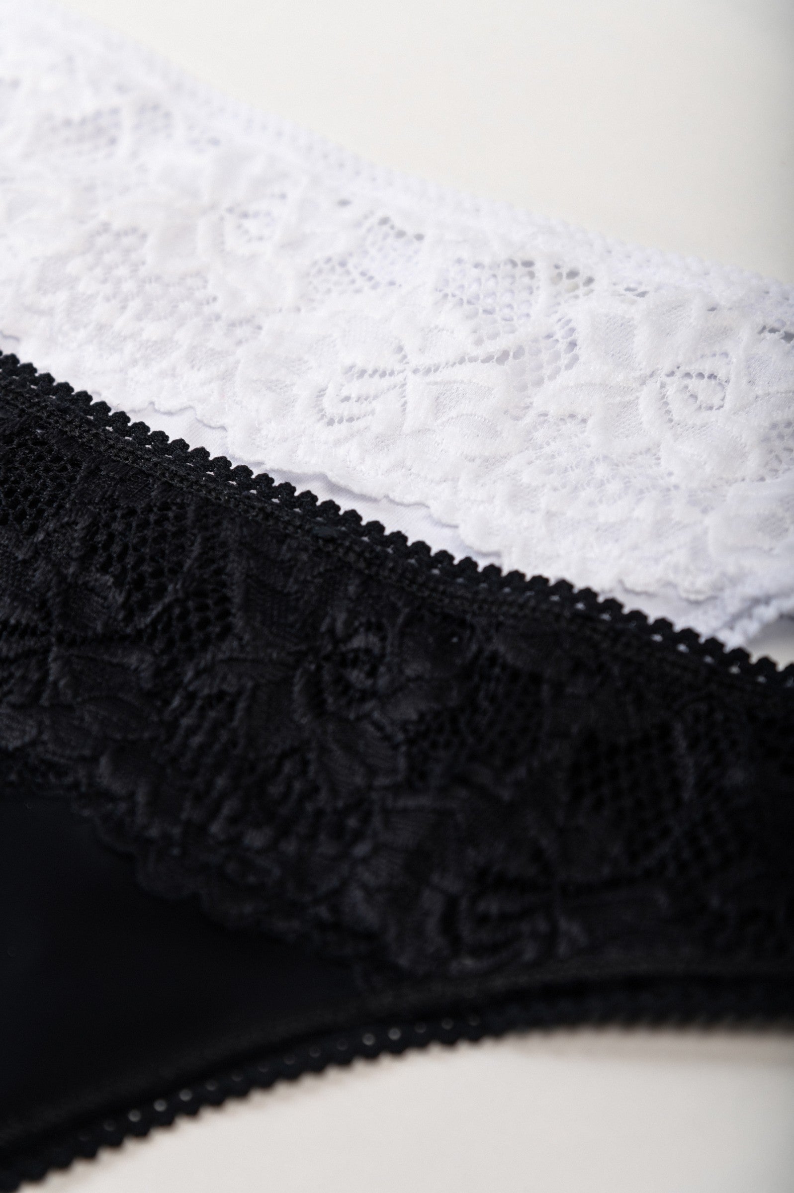 Set of two cotton thongs with lace in black and white, showcasing high-quality stretch cotton and elegant design.