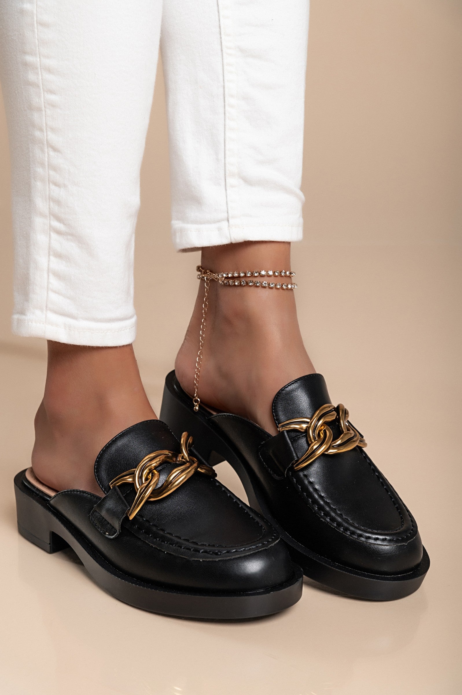 A pair of stylish black flat-soled shoes with decorative detail and round toe design, made from high-quality materials.