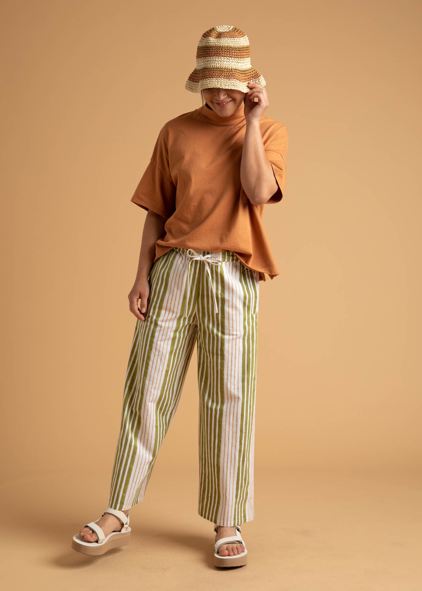 Shore Pant in Mixed Up Stripe Baked Clay & Olive Oil, showcasing a modern cropped design with a relaxed fit and elastic waist.