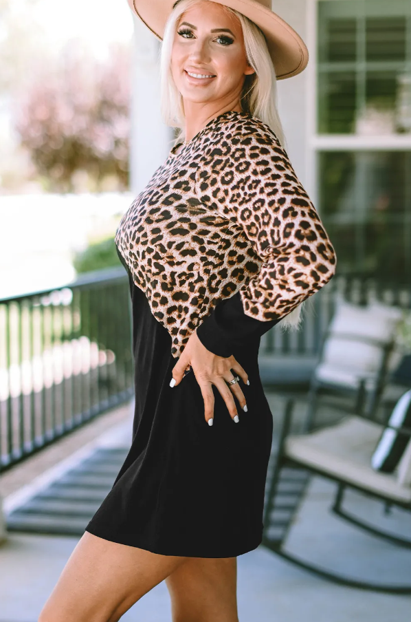 A stylish black mini dress featuring a trendy leopard print design, round neckline, and long sleeves, perfect for various occasions.