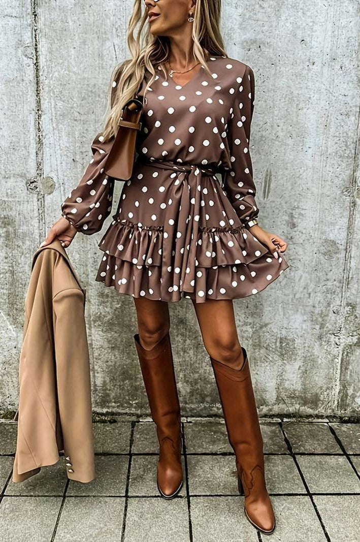 Brown mini dress with polka dot print, featuring a V-neckline, long sleeves, and a ruffled skirt, complete with a decorative belt.