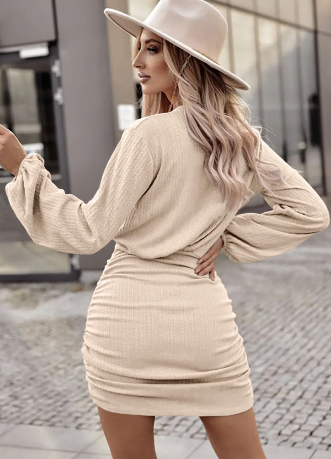 A stylish apricot short knitted dress featuring a round neckline, long sleeves, and a gathered mini skirt, perfect for casual and formal occasions.