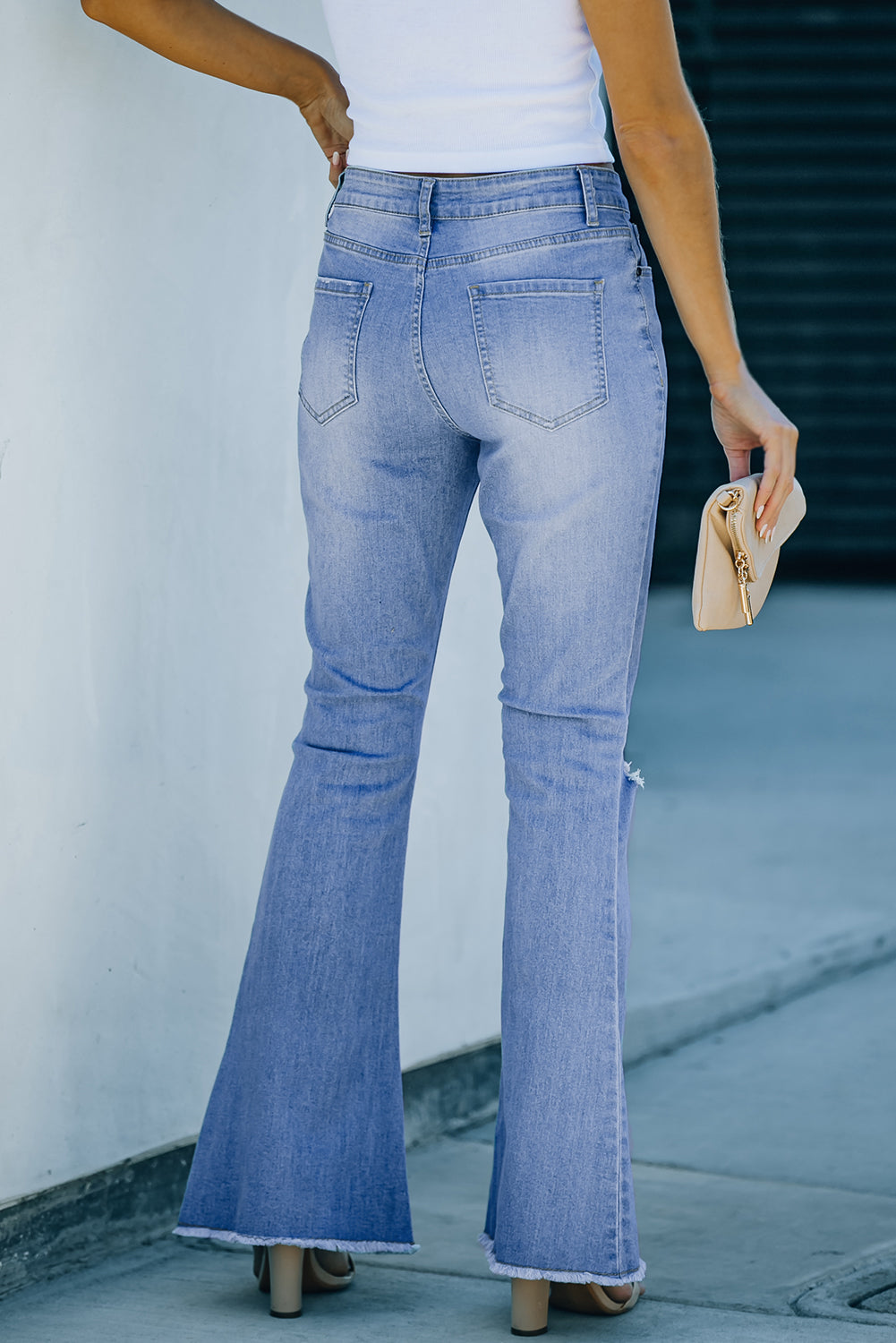 Sky Blue High Rise Distressed Bell Bottom Denims featuring a frayed hemline and knee distressing, perfect for a trendy look.
