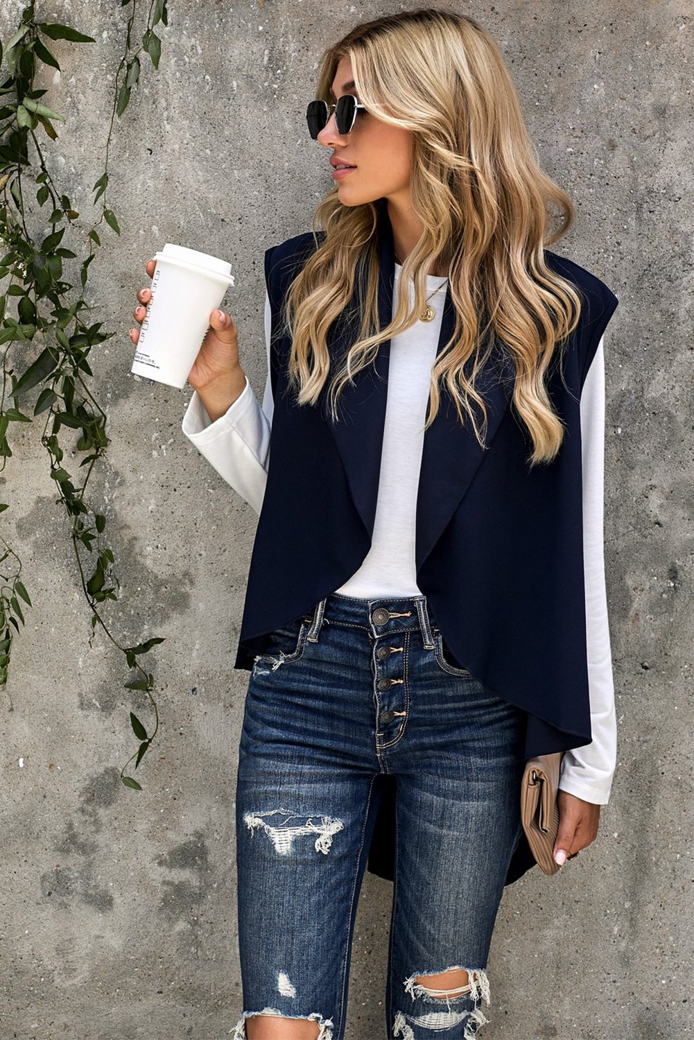 A stylish sleeveless cascade open front draped cardigan with a shawl neckline, showcasing a high-low hemline, perfect for layering.