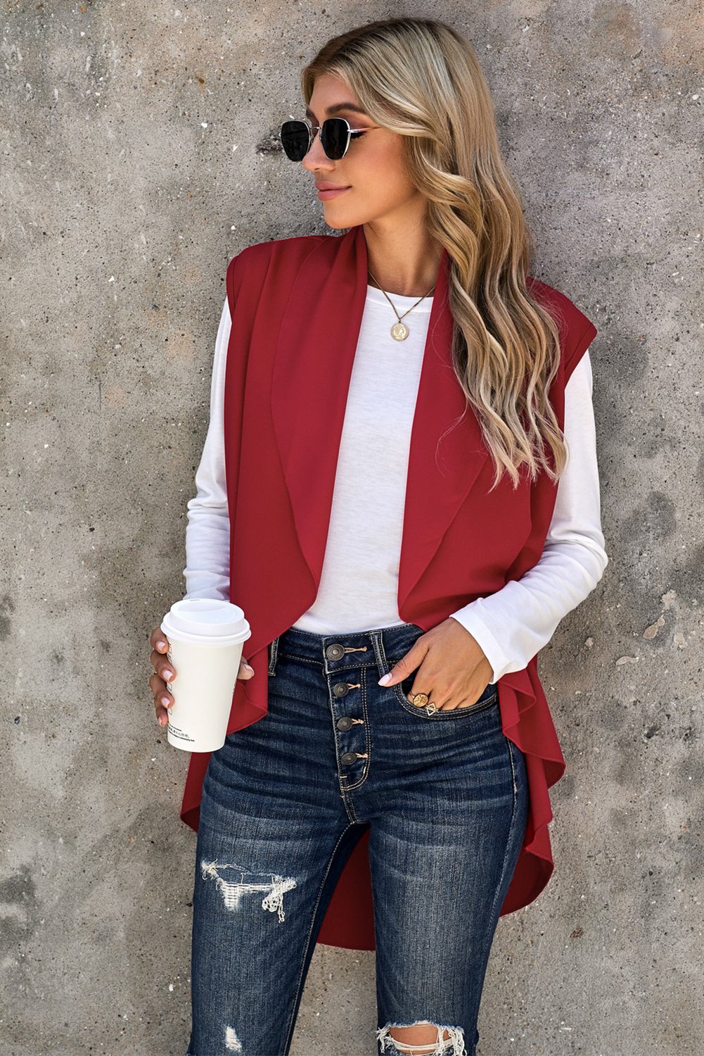 A stylish sleeveless cascade open front draped cardigan with a shawl neckline, showcasing a high-low hemline, perfect for layering.