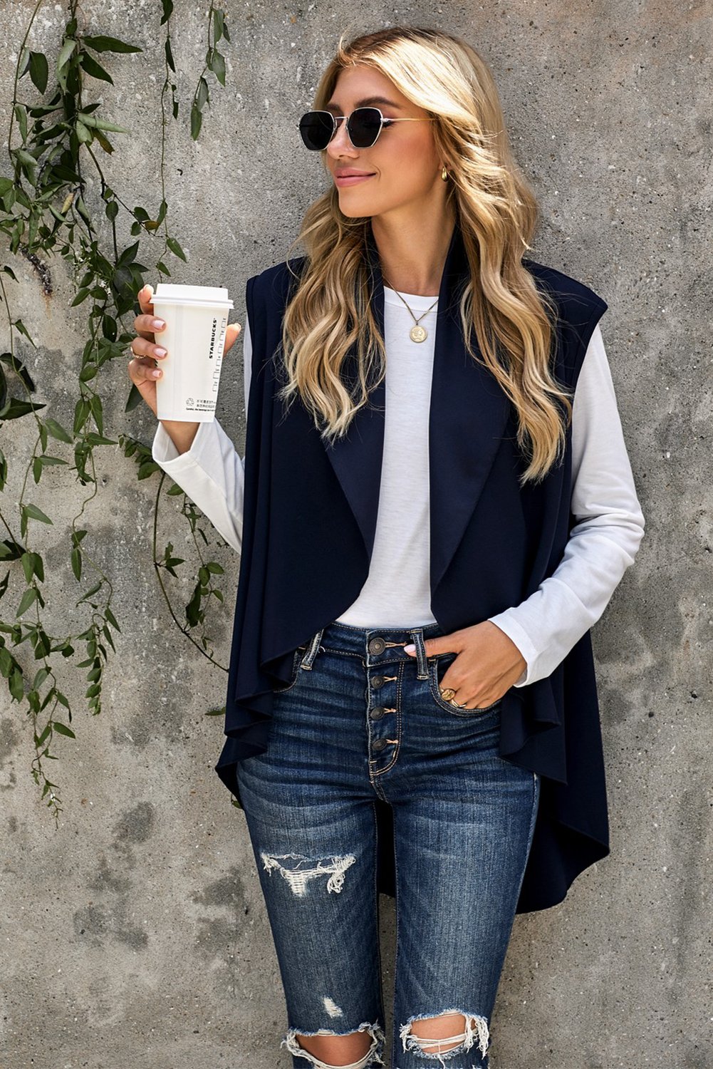 A stylish sleeveless cascade open front draped cardigan with a shawl neckline, showcasing a high-low hemline, perfect for layering.