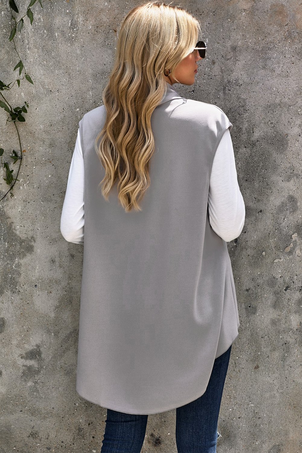 A stylish sleeveless cascade open front draped cardigan with a shawl neckline, showcasing a high-low hemline, perfect for layering.