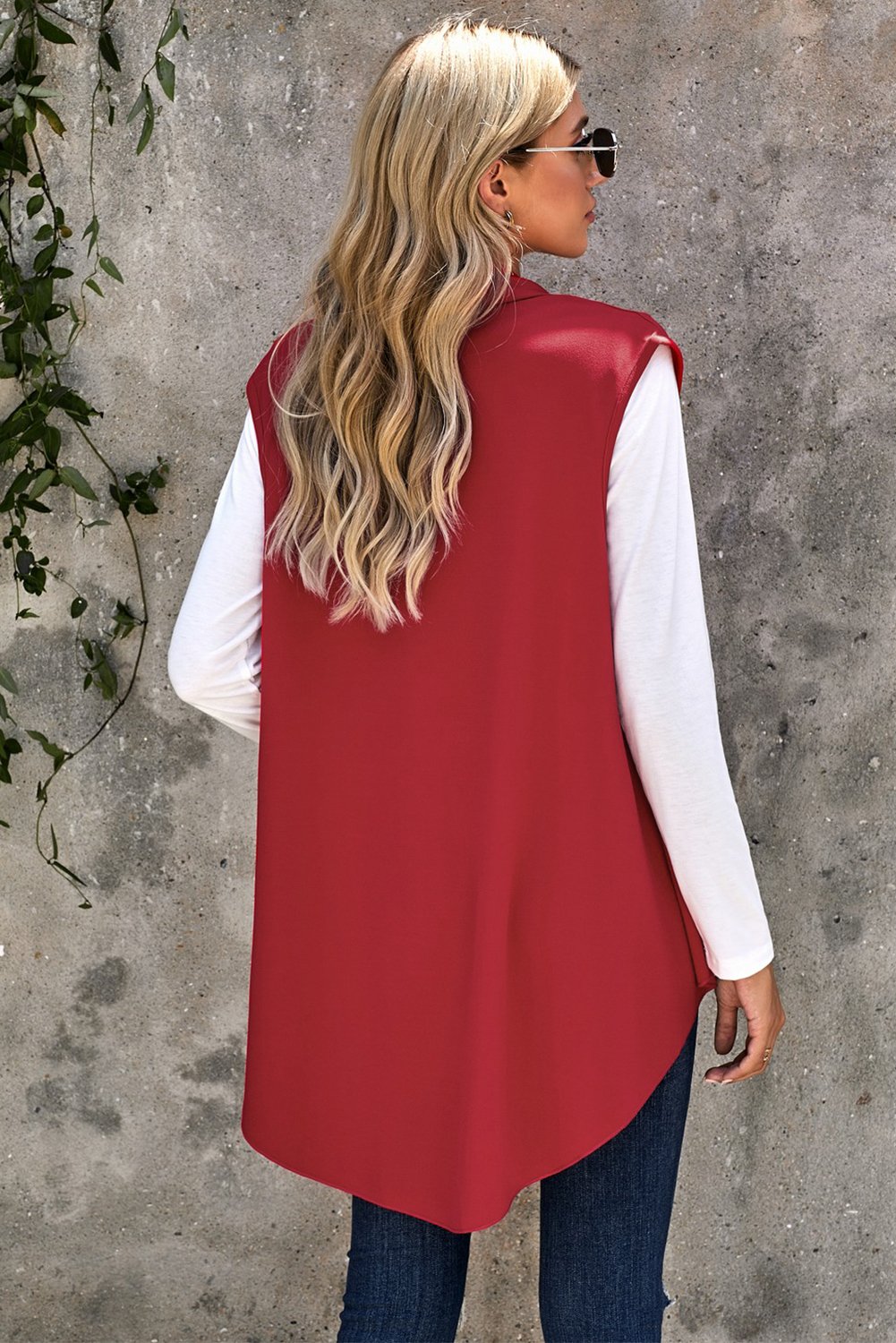 A stylish sleeveless cascade open front draped cardigan with a shawl neckline, showcasing a high-low hemline, perfect for layering.