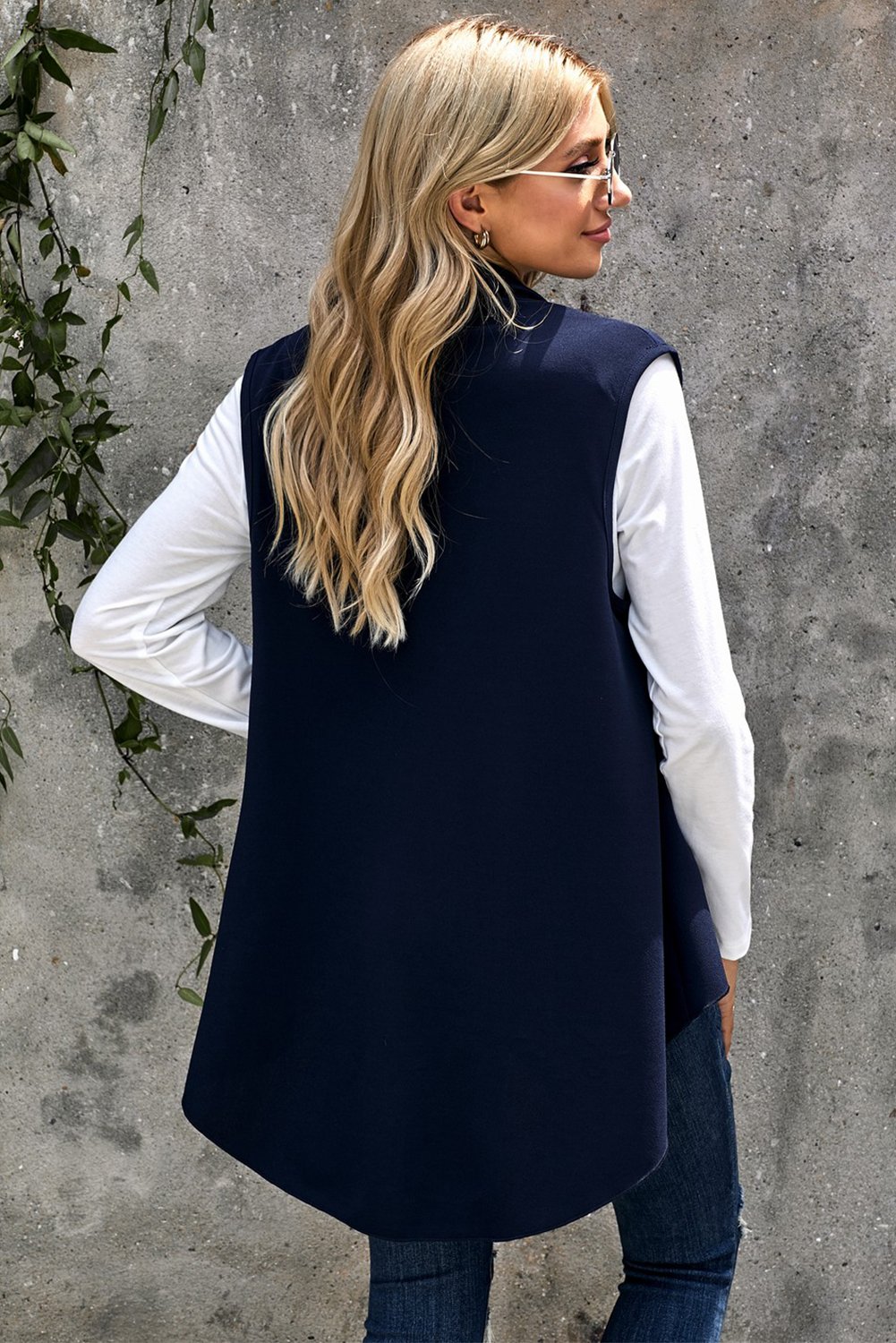 A stylish sleeveless cascade open front draped cardigan with a shawl neckline, showcasing a high-low hemline, perfect for layering.