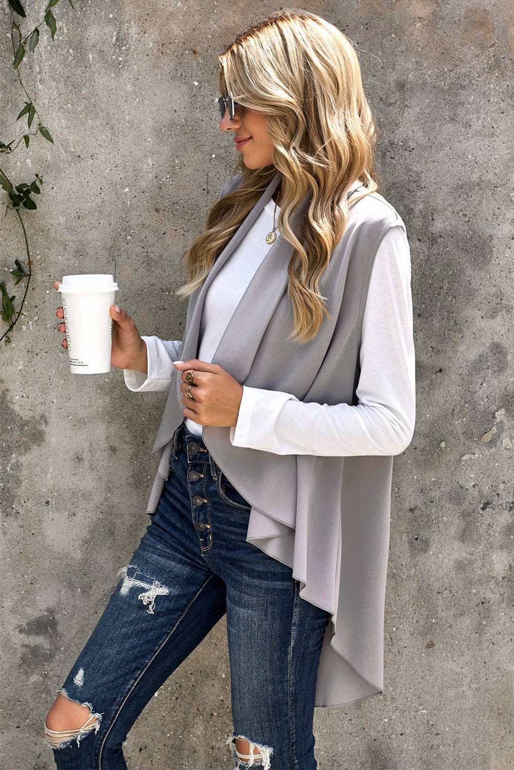 A stylish sleeveless cascade open front draped cardigan with a shawl neckline, showcasing a high-low hemline, perfect for layering.