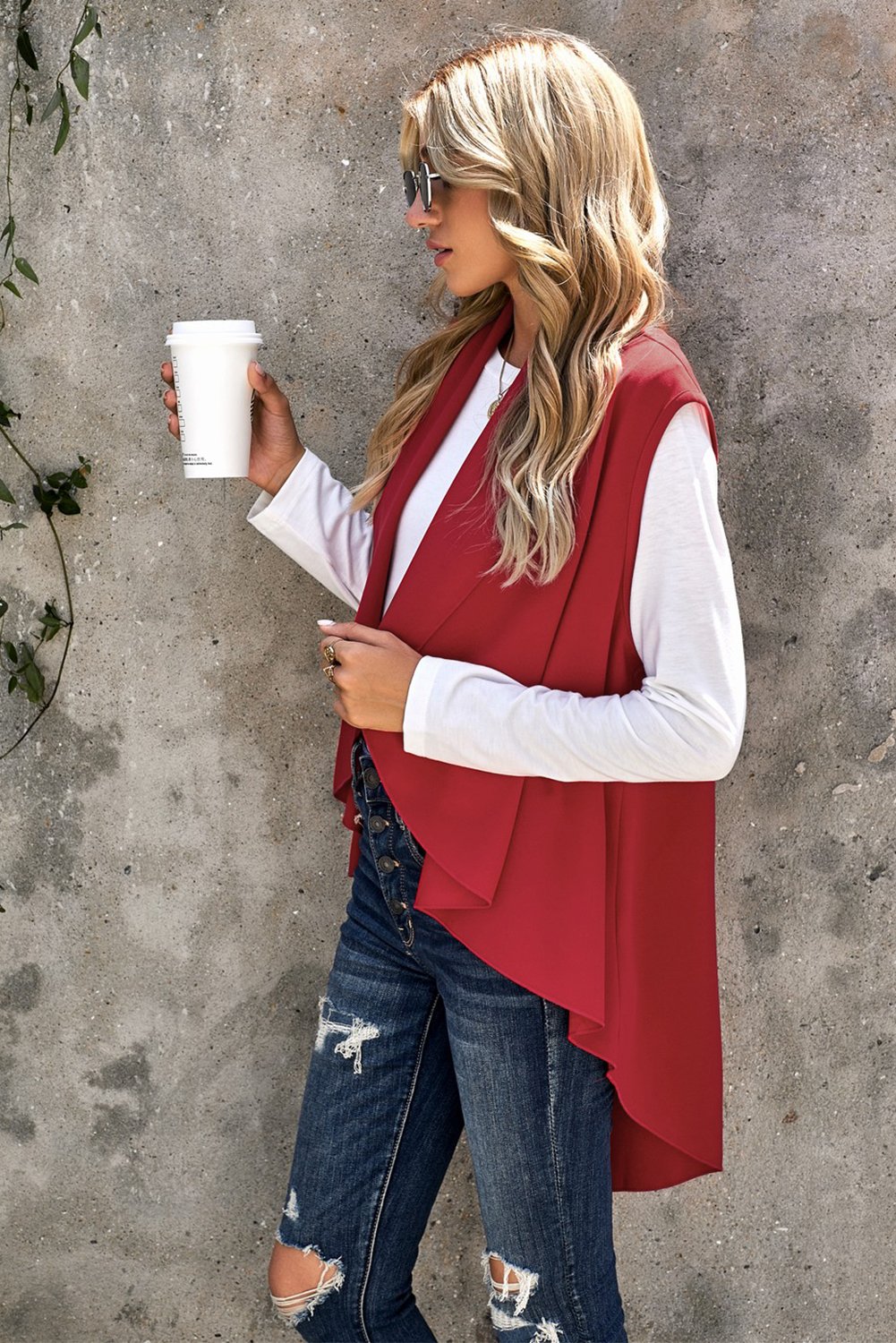 A stylish sleeveless cascade open front draped cardigan with a shawl neckline, showcasing a high-low hemline, perfect for layering.
