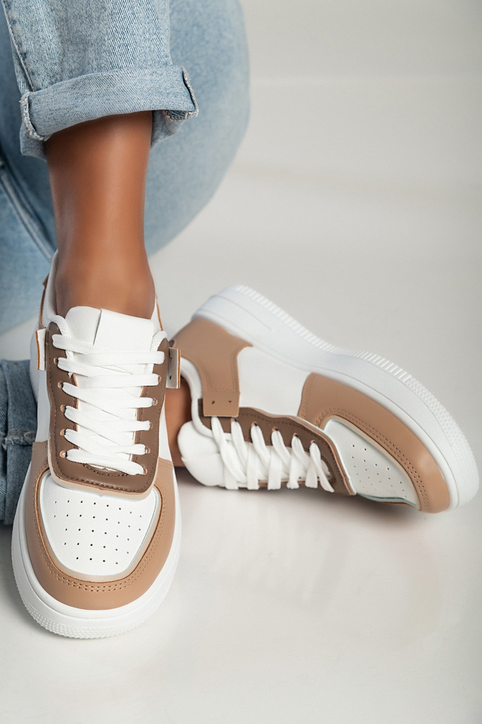 Camel color sneakers with flat sole, round toe, and bows, made of synthetic leather.