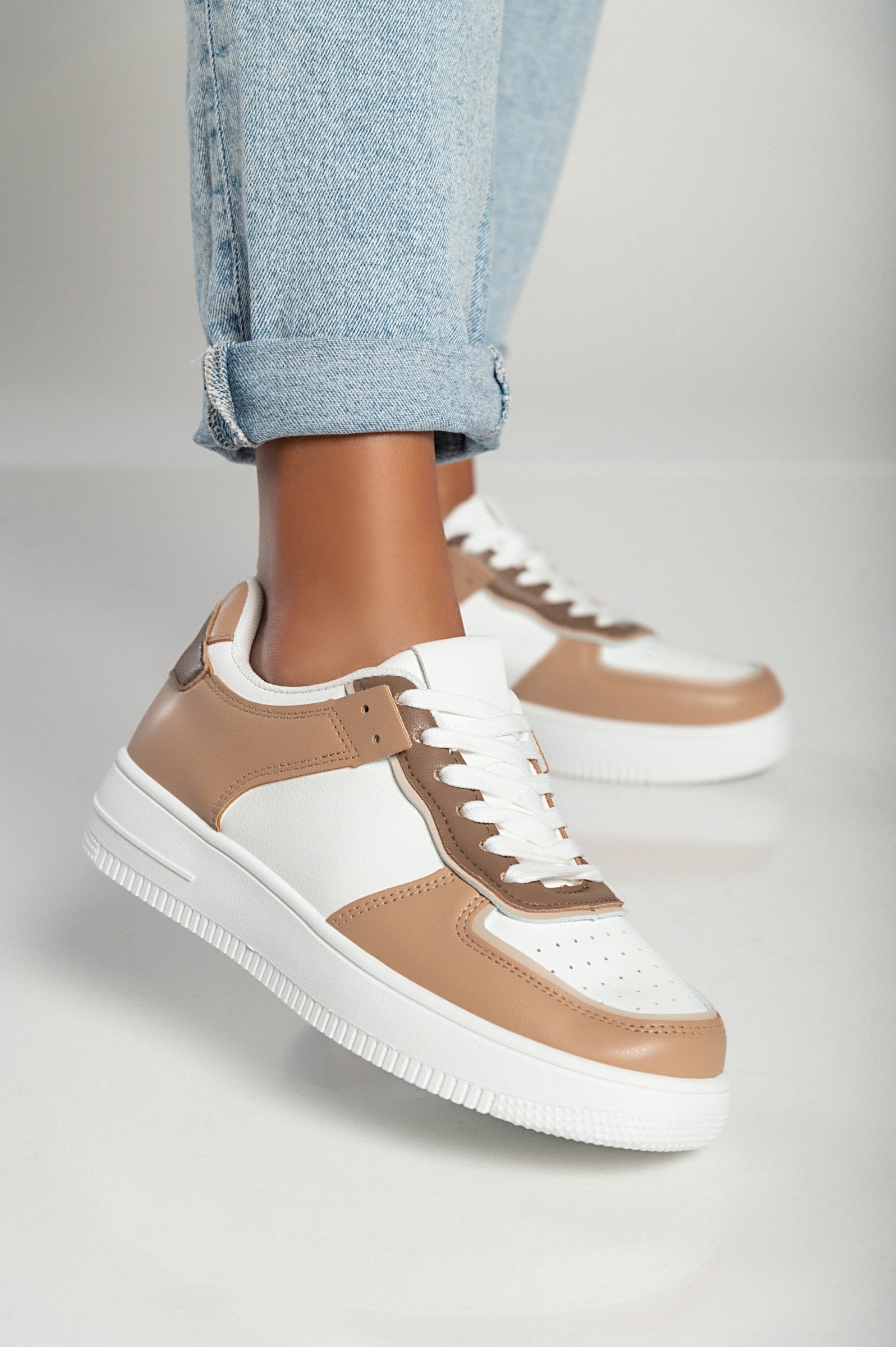 Camel color sneakers with flat sole, round toe, and bows, made of synthetic leather.