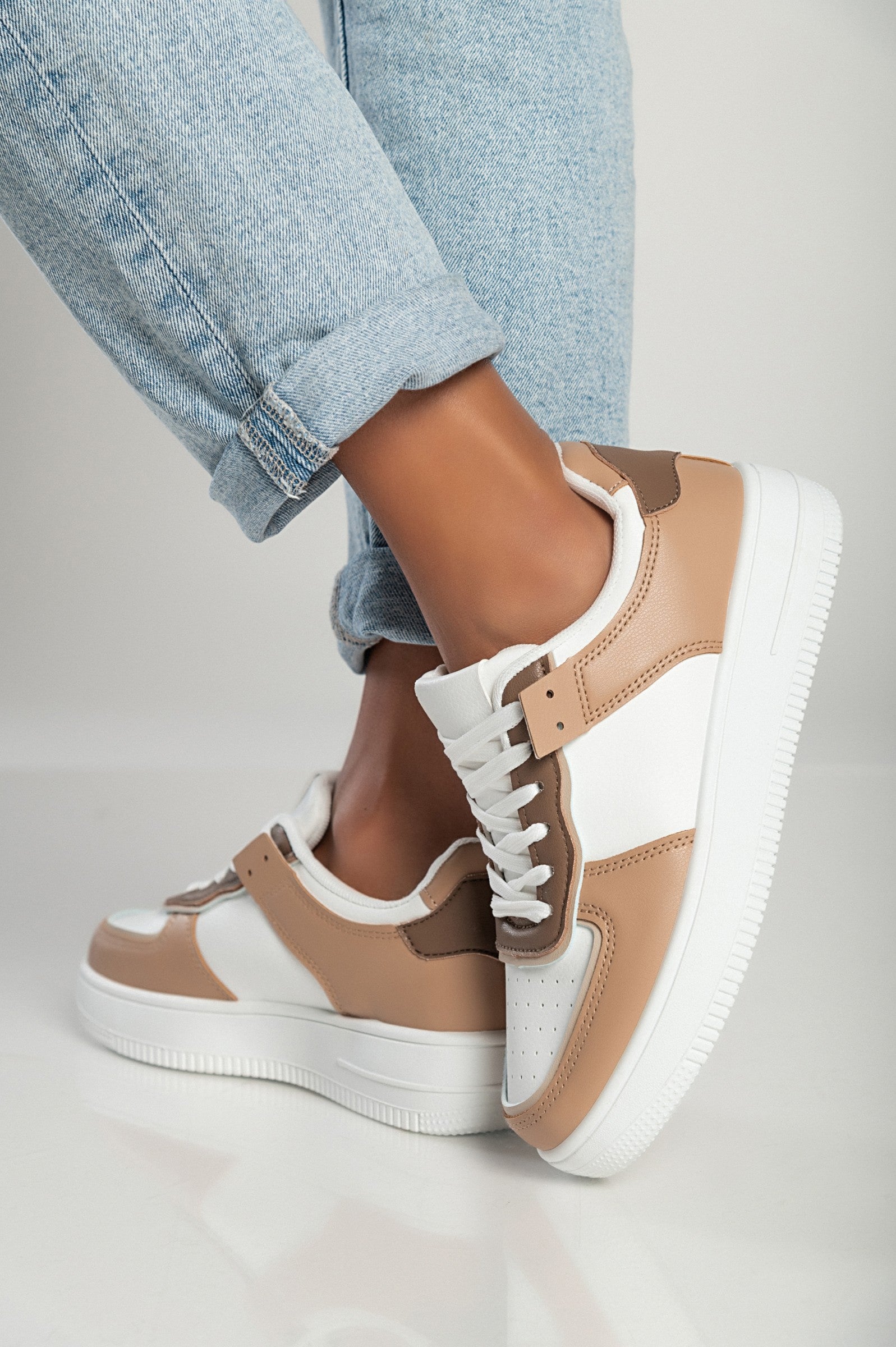 Camel color sneakers with flat sole, round toe, and bows, made of synthetic leather.