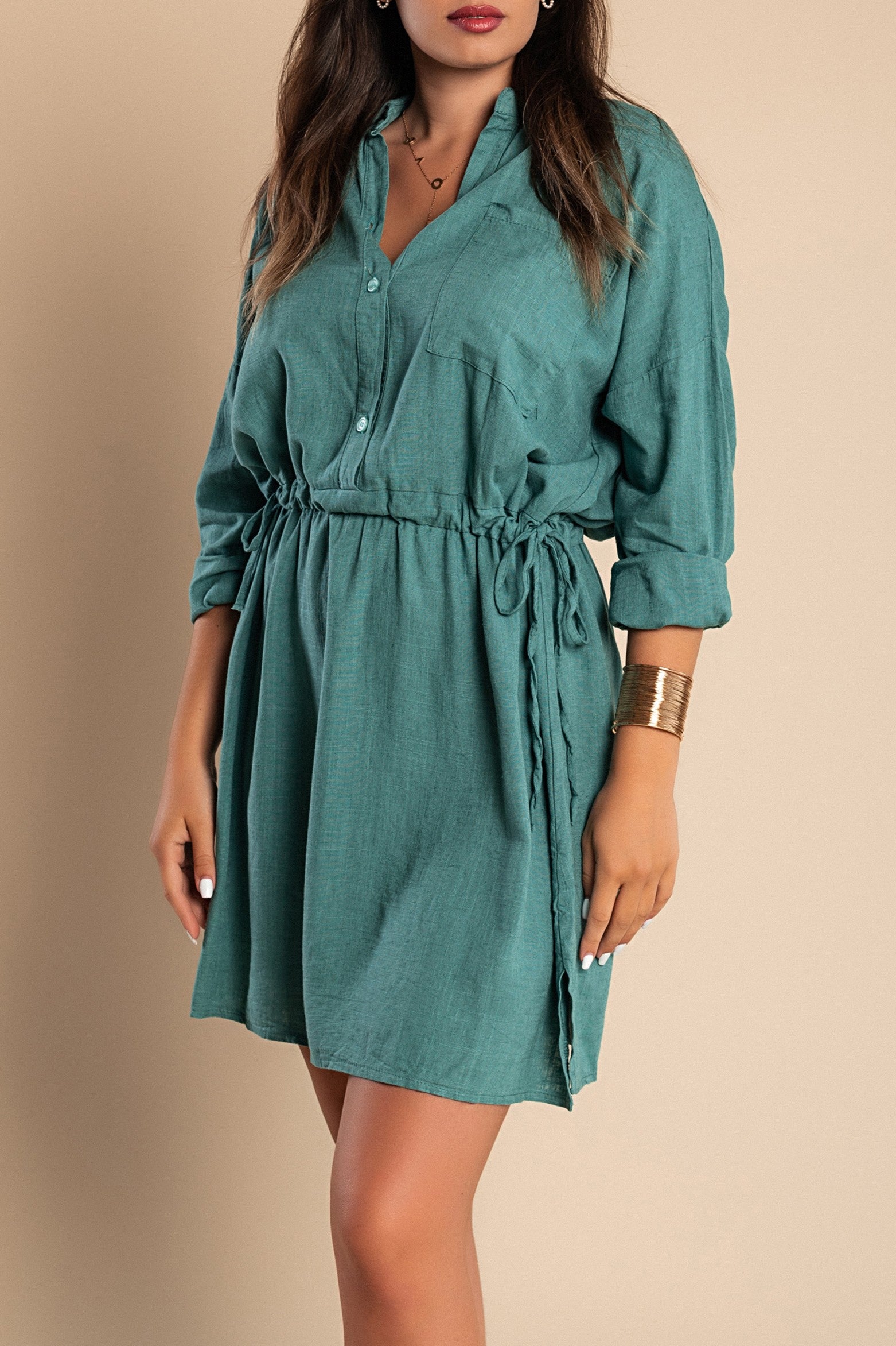 A stylish petroleum-colored mini dress featuring a classic collar, long sleeves, front button closure, and a decorative pocket, perfect for various occasions.