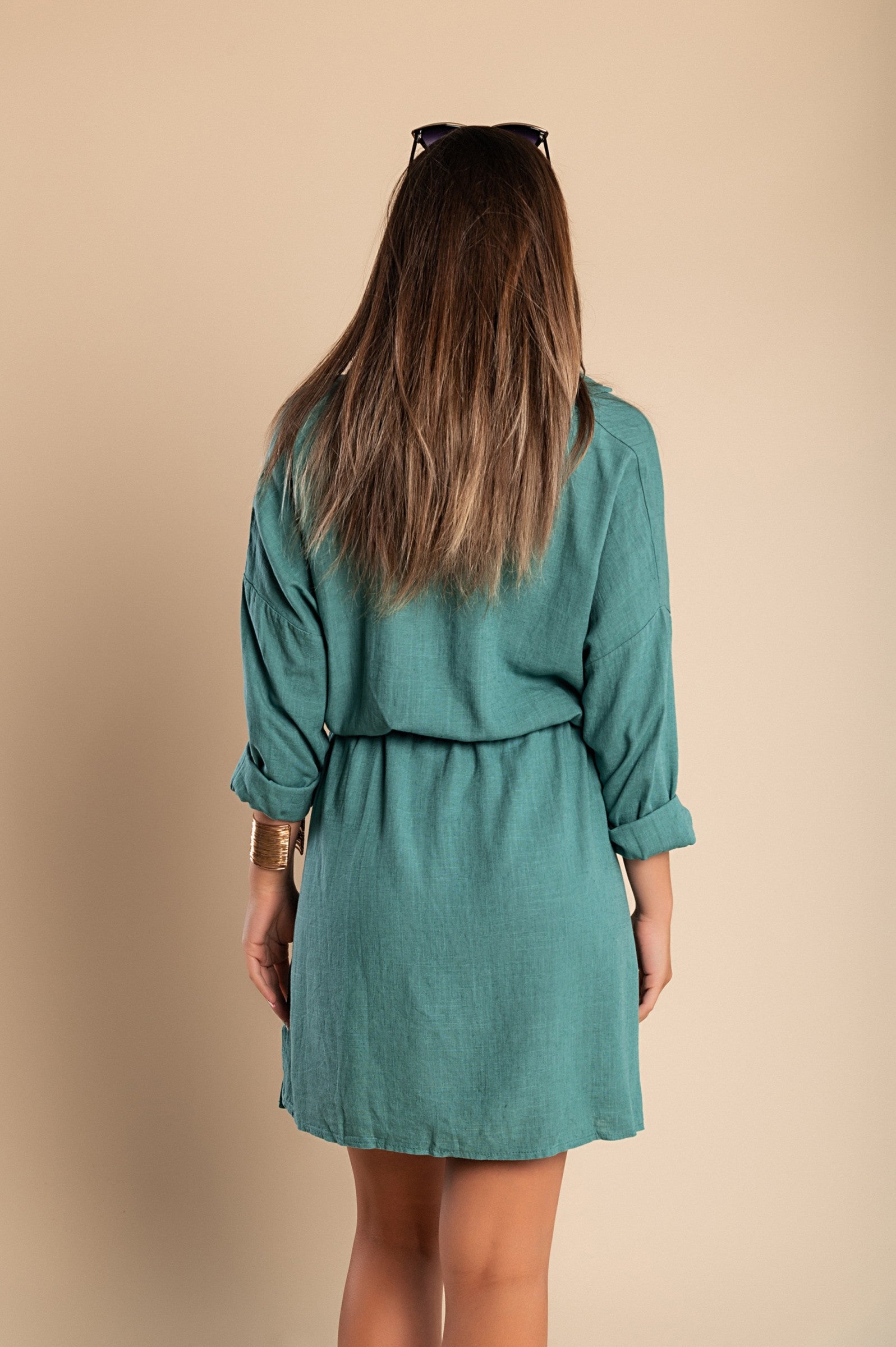 A stylish petroleum-colored mini dress featuring a classic collar, long sleeves, front button closure, and a decorative pocket, perfect for various occasions.