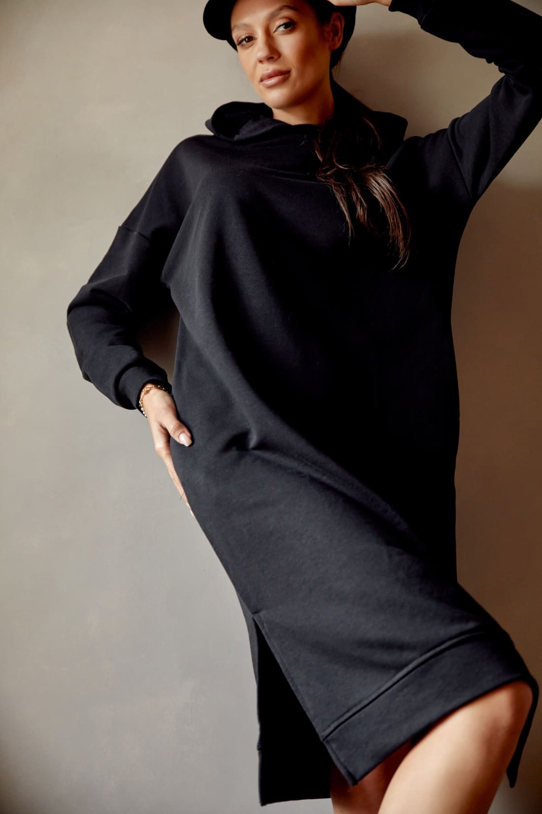 Black sports midi dress with hood, featuring long sleeves, side pockets, and side slits, made from soft cotton fabric.