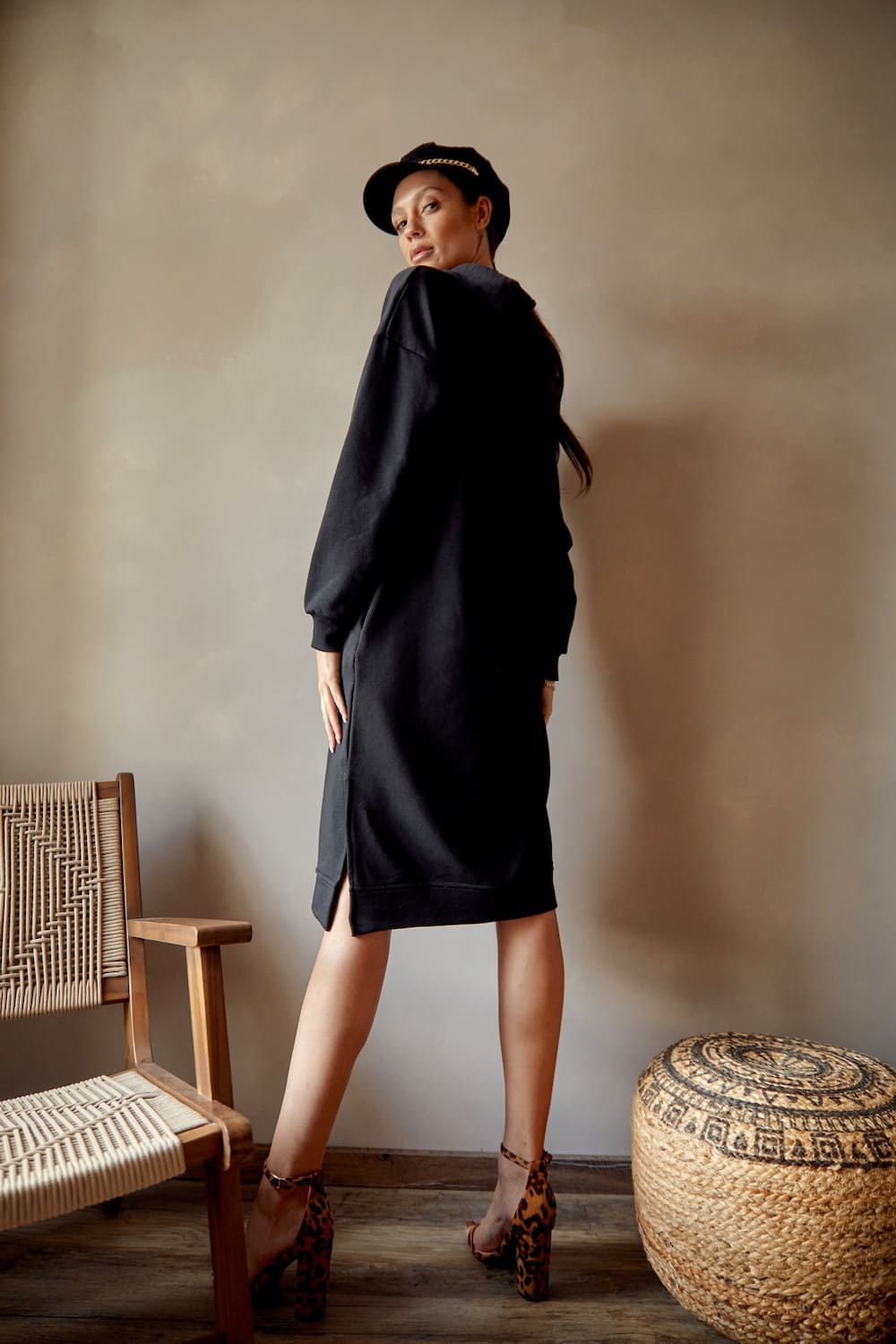 Black sports midi dress with hood, featuring long sleeves, side pockets, and side slits, made from soft cotton fabric.