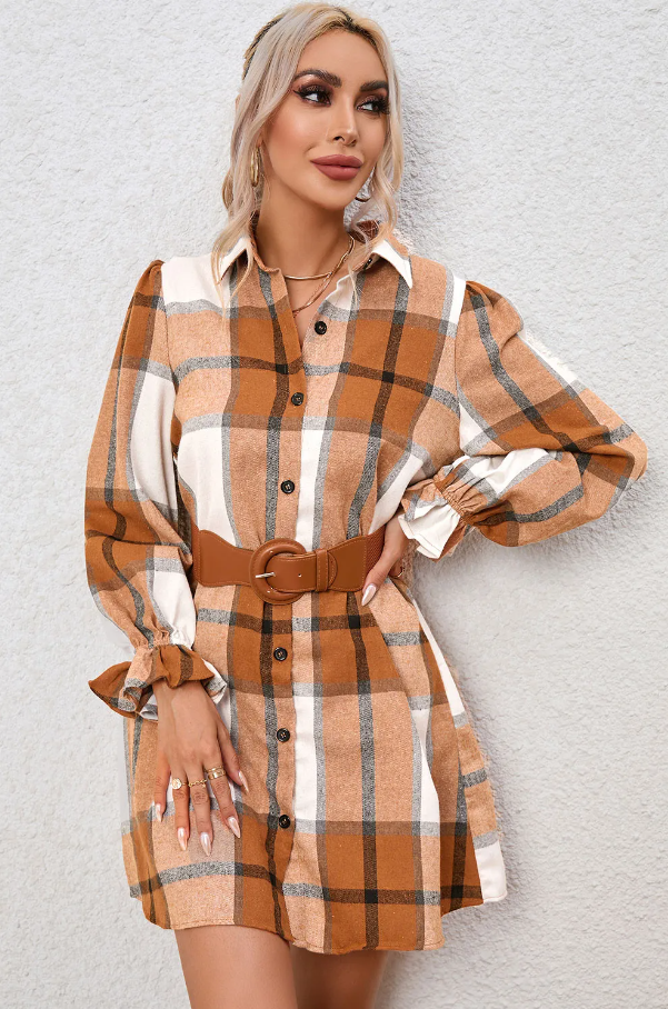 Mini srajčna obleka s karo potiskom v kaki barvi, ohlapnega kroja z dolgimi rokavi in gumbnim zapenjanjem.