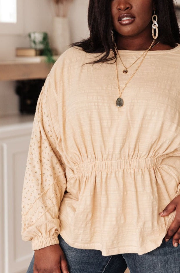 A stylish peach floral top featuring balloon dolman sleeves and an elastic waistband, perfect for a feminine look.