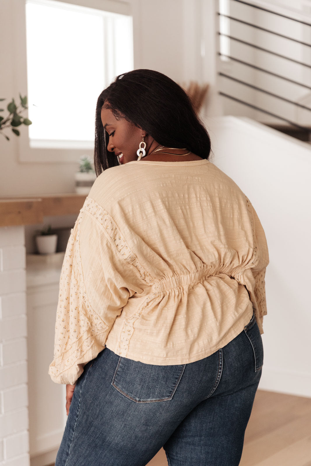 A stylish peach floral top featuring balloon dolman sleeves and an elastic waistband, perfect for a feminine look.