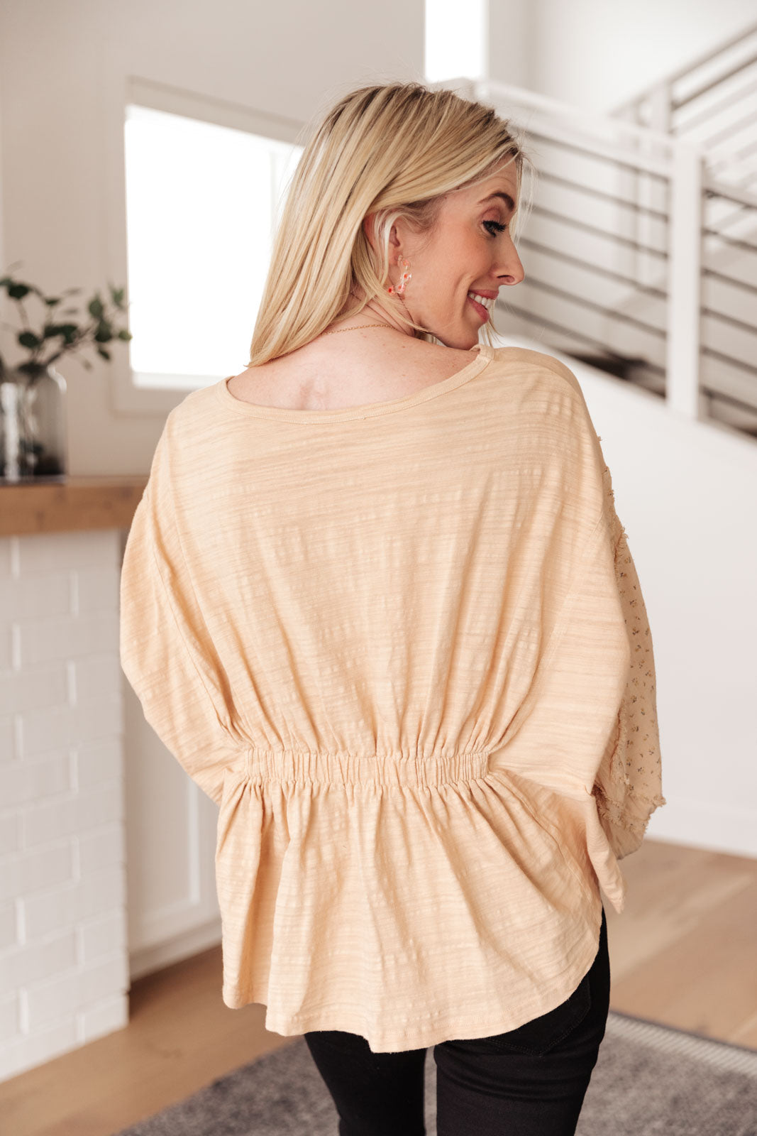 A stylish peach floral top featuring balloon dolman sleeves and an elastic waistband, perfect for a feminine look.