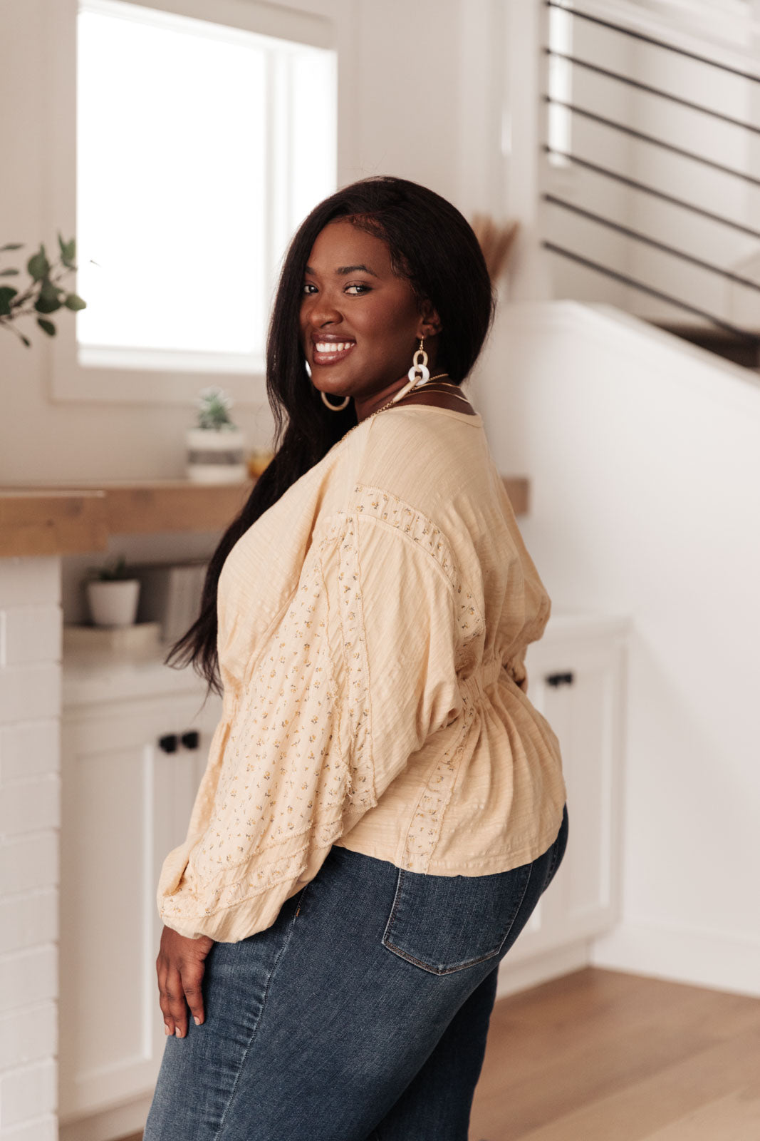 A stylish peach floral top featuring balloon dolman sleeves and an elastic waistband, perfect for a feminine look.