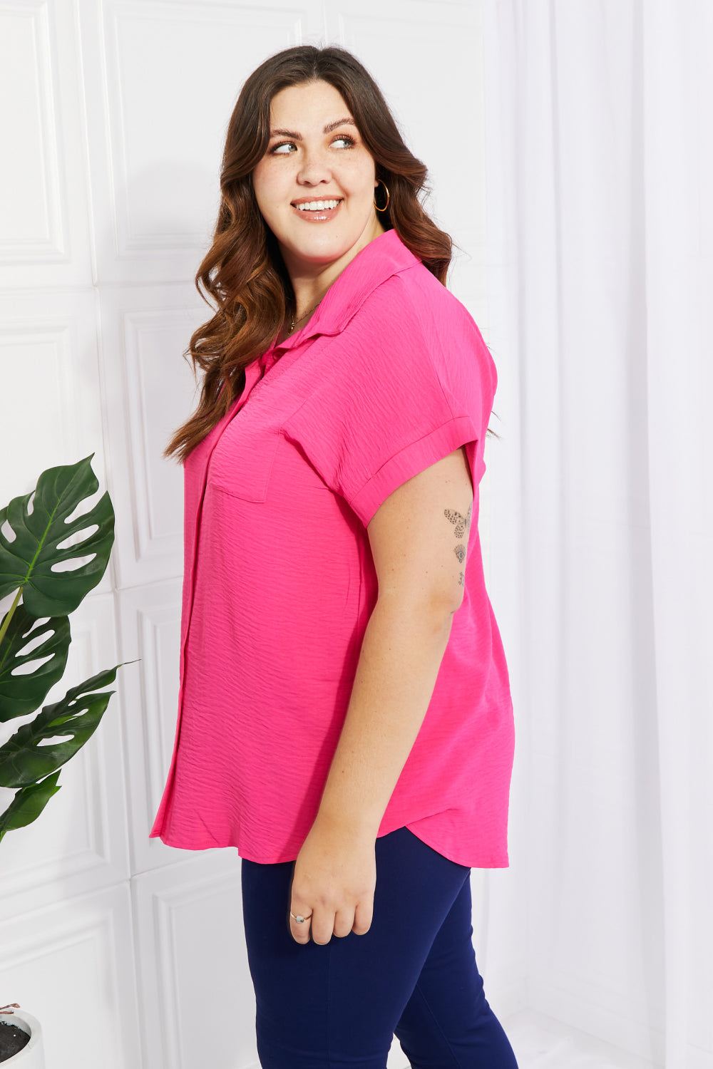 A stylish long-length button-up shirt with a curved hem, short cuffed sleeves, and breast pockets, perfect for warm weather.