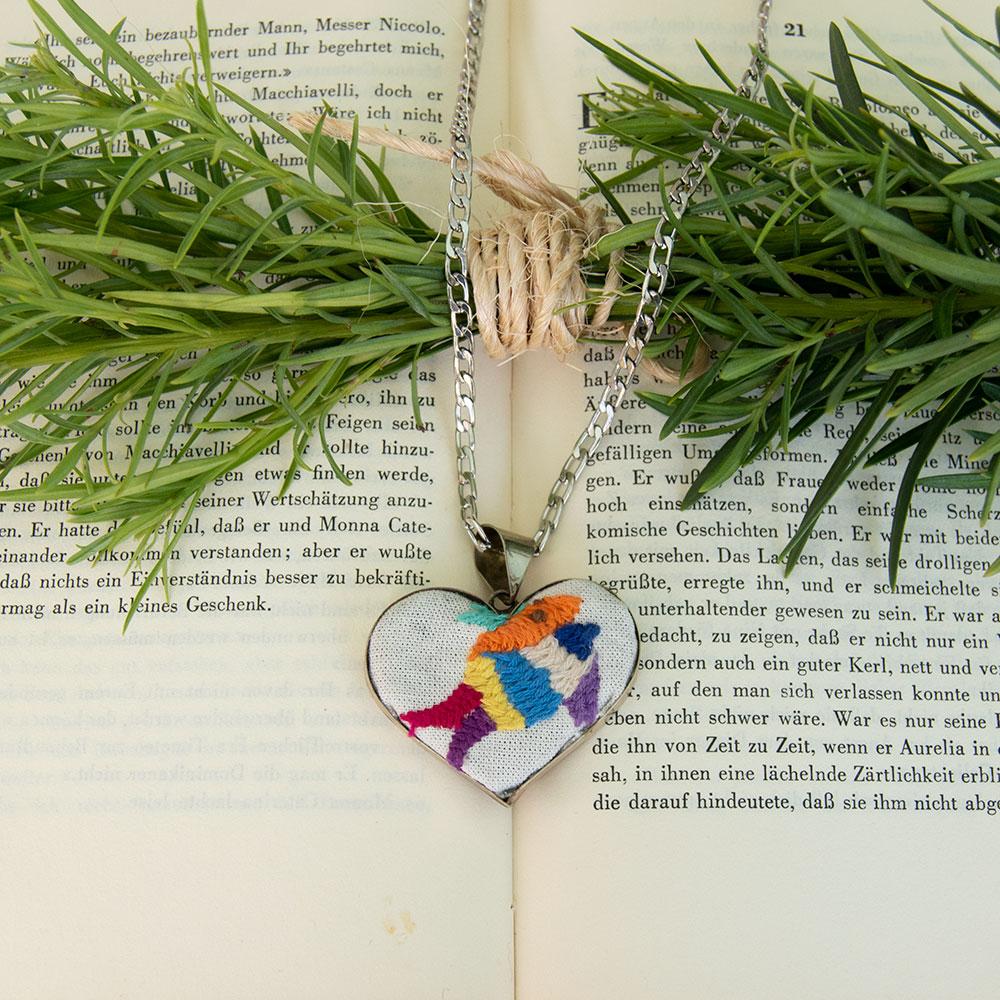 Colorful Tenango de Doria Embroidered Heart Necklace with unique Otomi embroidery on aluminum pendant.