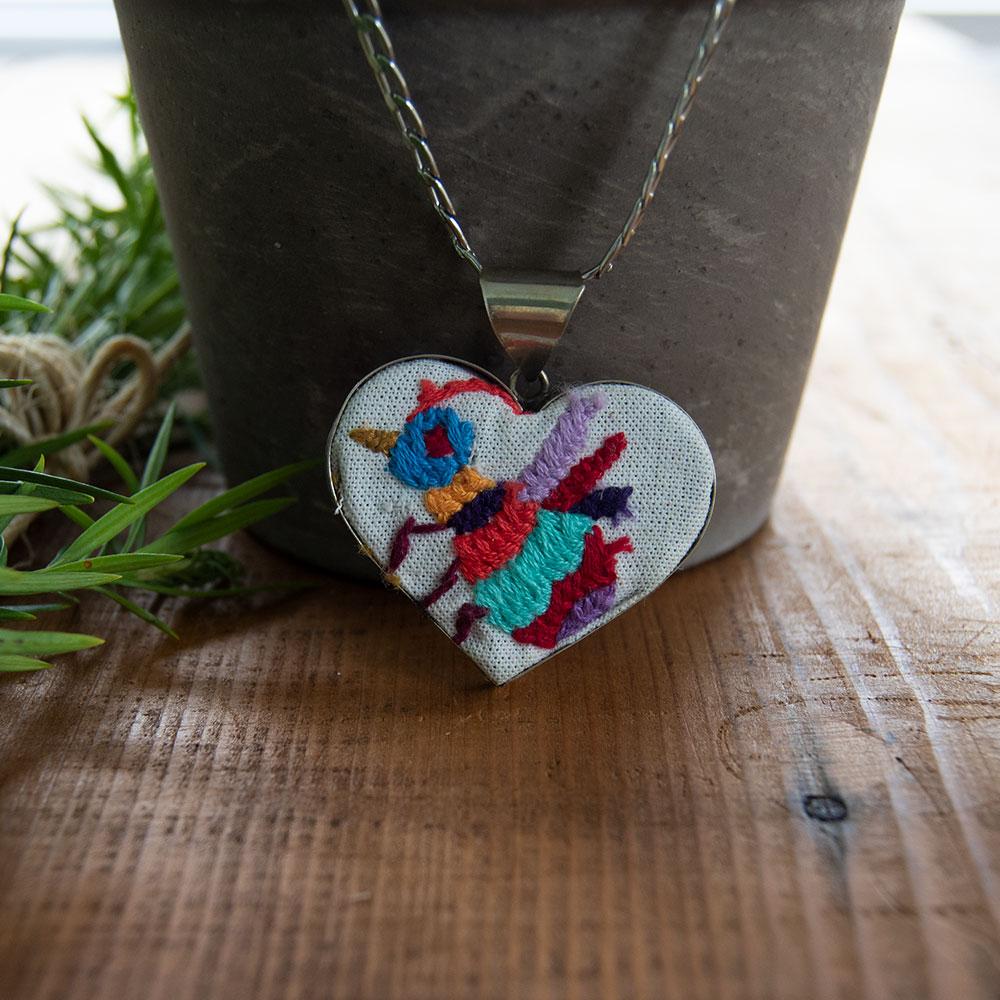 Colorful Tenango de Doria Embroidered Heart Necklace with unique Otomi embroidery on aluminum pendant.
