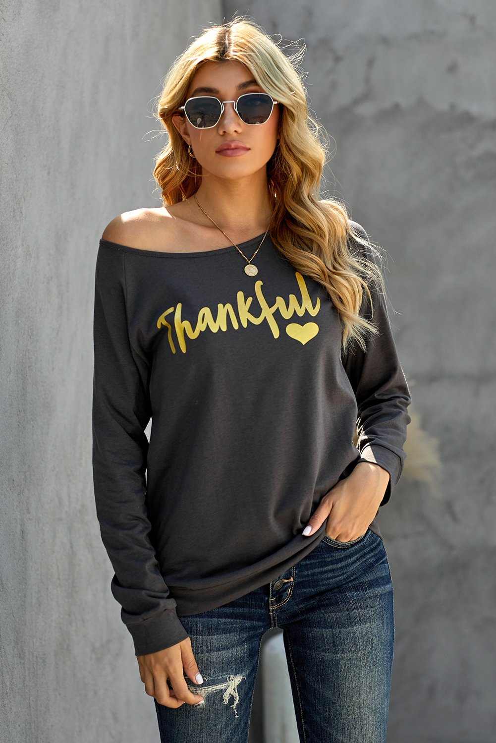 A stylish woman wearing the THANKFUL Print Off Shoulder Long Sleeve Top, showcasing its elegant off-shoulder design and unique print detail.