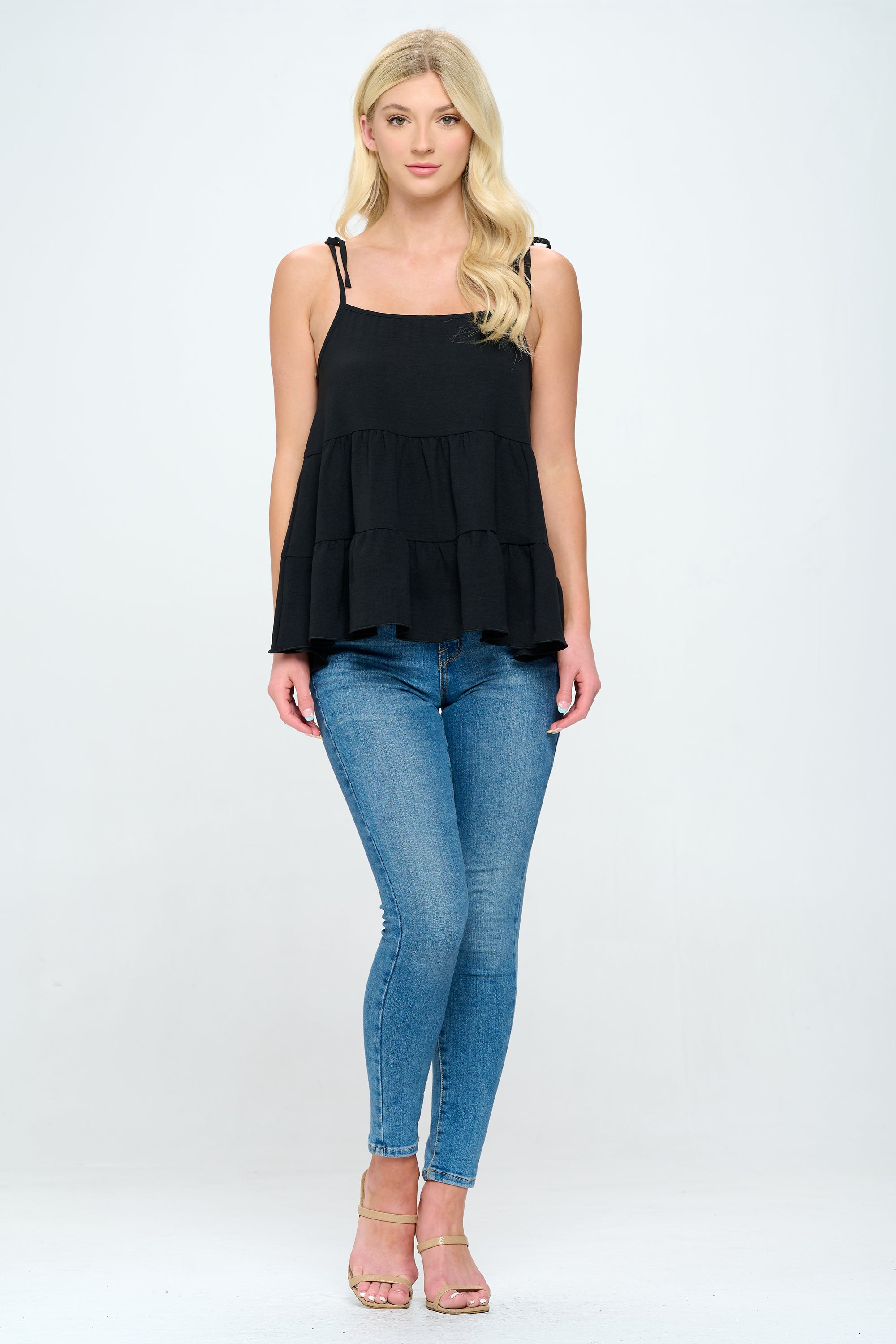 A stylish tiered sleeveless top with adjustable straps, featuring a loose fit and flared bottom in solid airflow fabric.