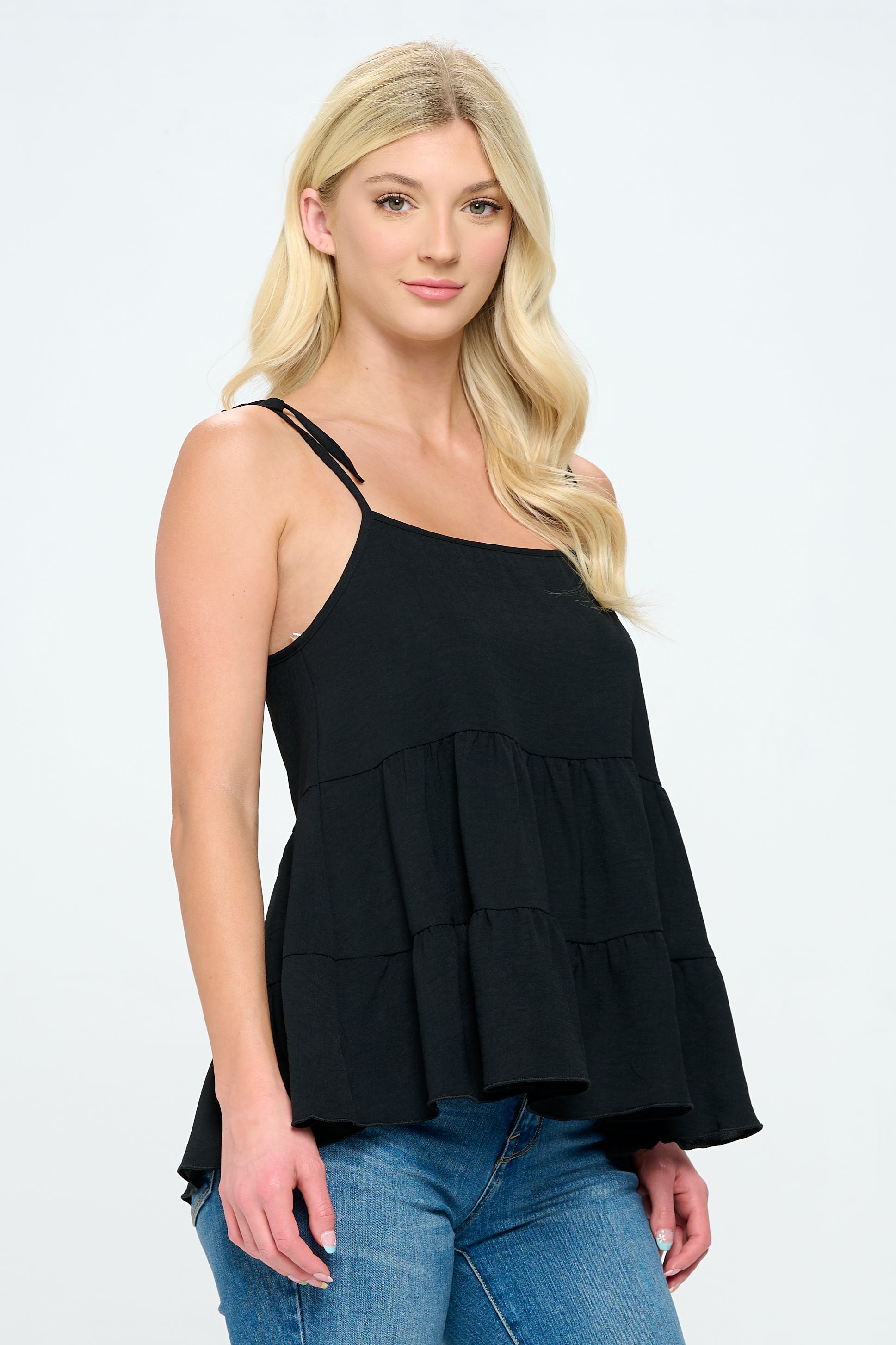 A stylish tiered sleeveless top with adjustable straps, featuring a loose fit and flared bottom in solid airflow fabric.