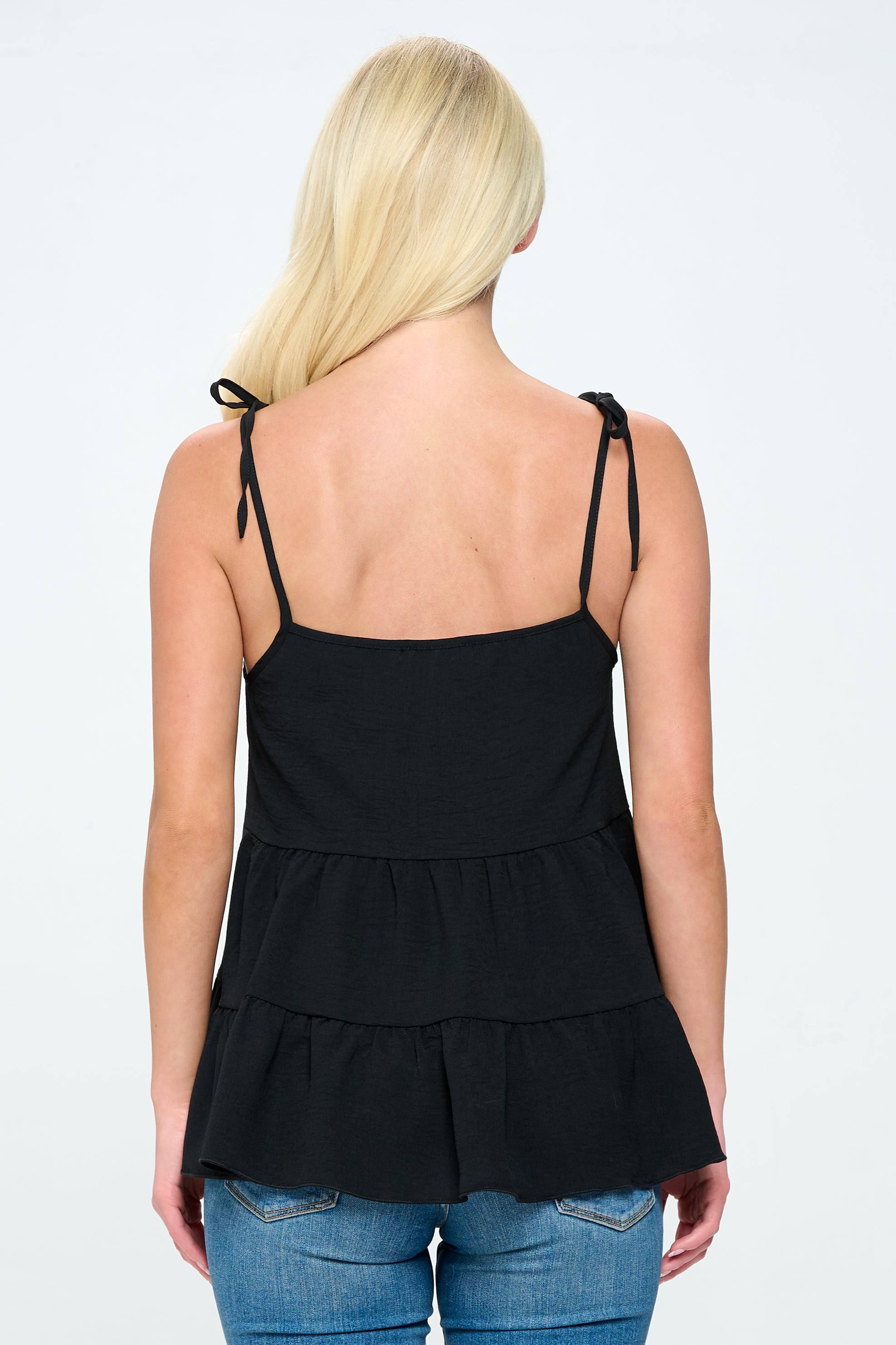 A stylish tiered sleeveless top with adjustable straps, featuring a loose fit and flared bottom in solid airflow fabric.
