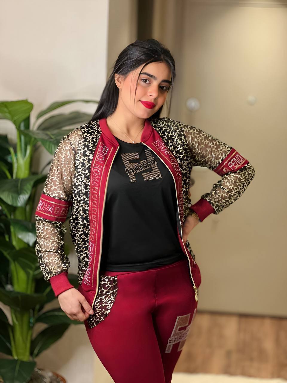 A stylish three-piece matching set featuring a transparent jacket with mesh sleeves, a sleeveless graphic top, and matching pants, perfect for chic fashion.