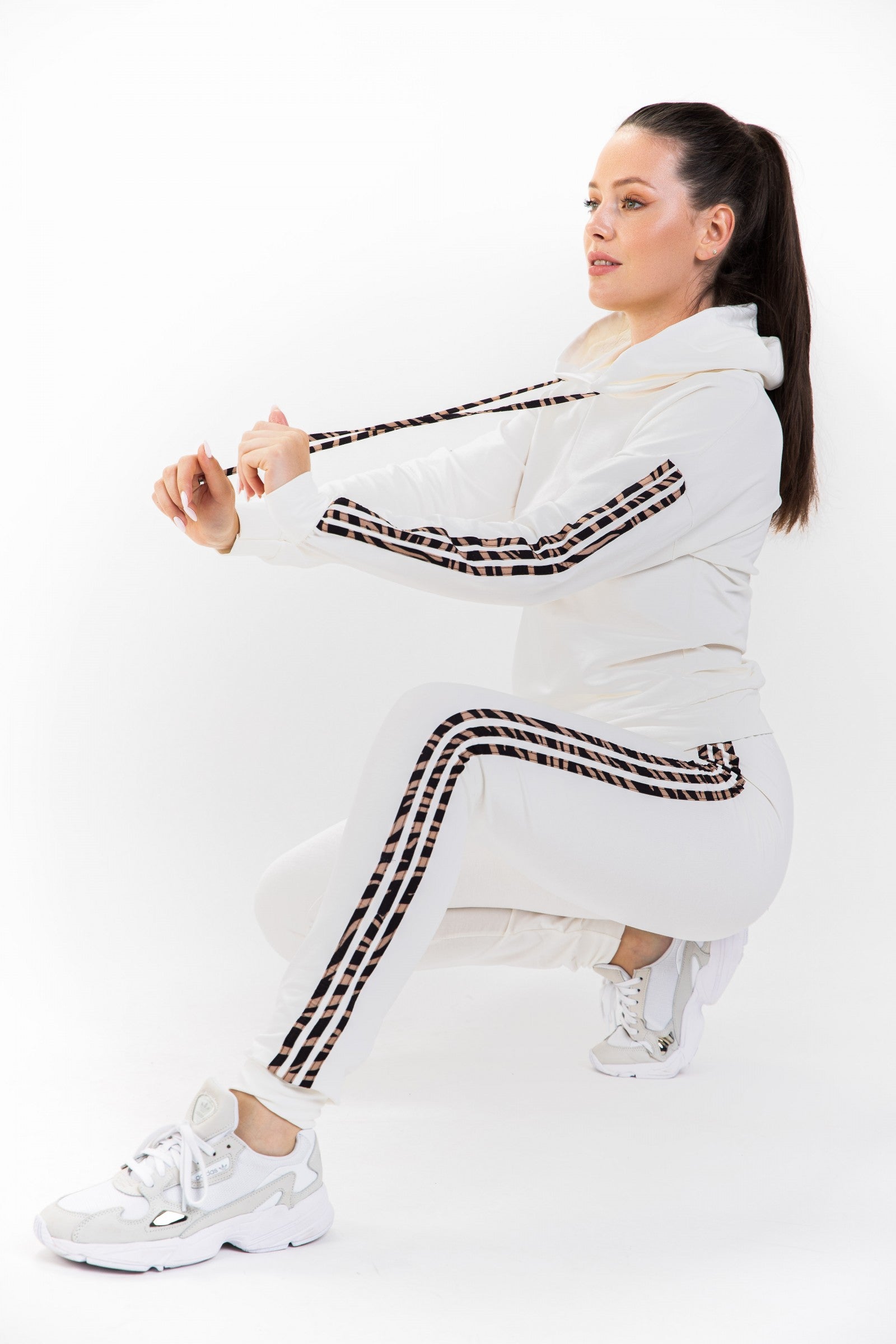 Trenirka komplet s potiskom in kapuco Andry v smetani, sestavljena iz majice in dolgih hlač, izdelana iz kakovostnega bombaža.