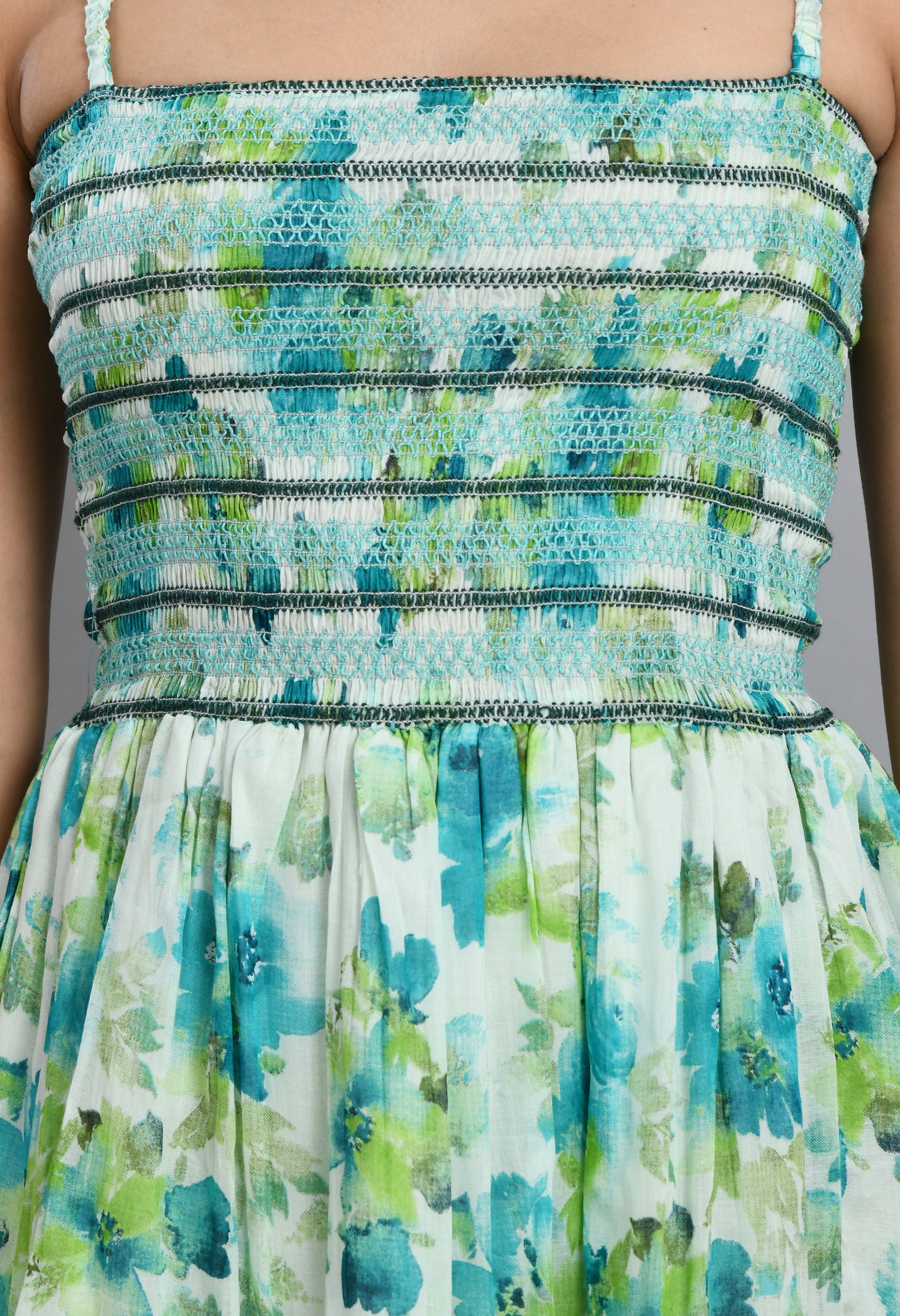 A stylish turquoise smoking short dress with floral pattern, sleeveless design, and asymmetrical hem, perfect for casual wear.