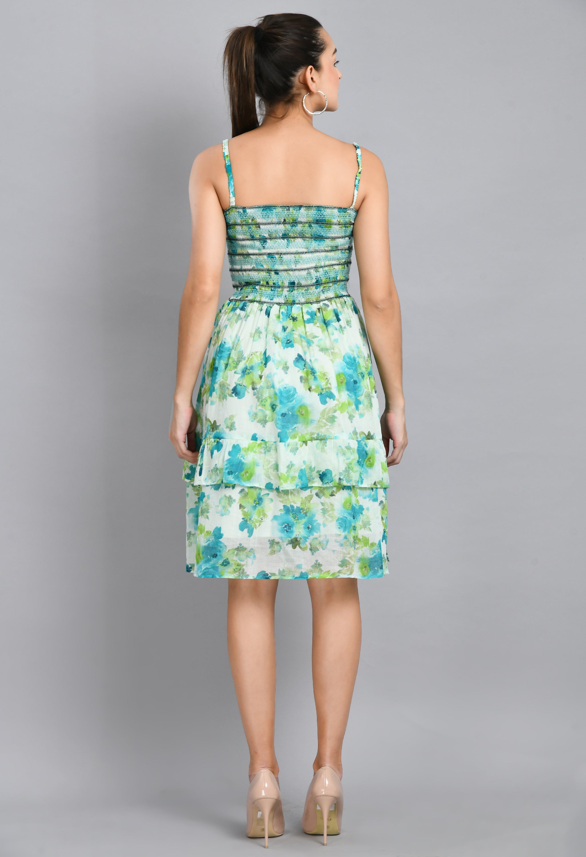 A stylish turquoise smoking short dress with floral pattern, sleeveless design, and asymmetrical hem, perfect for casual wear.