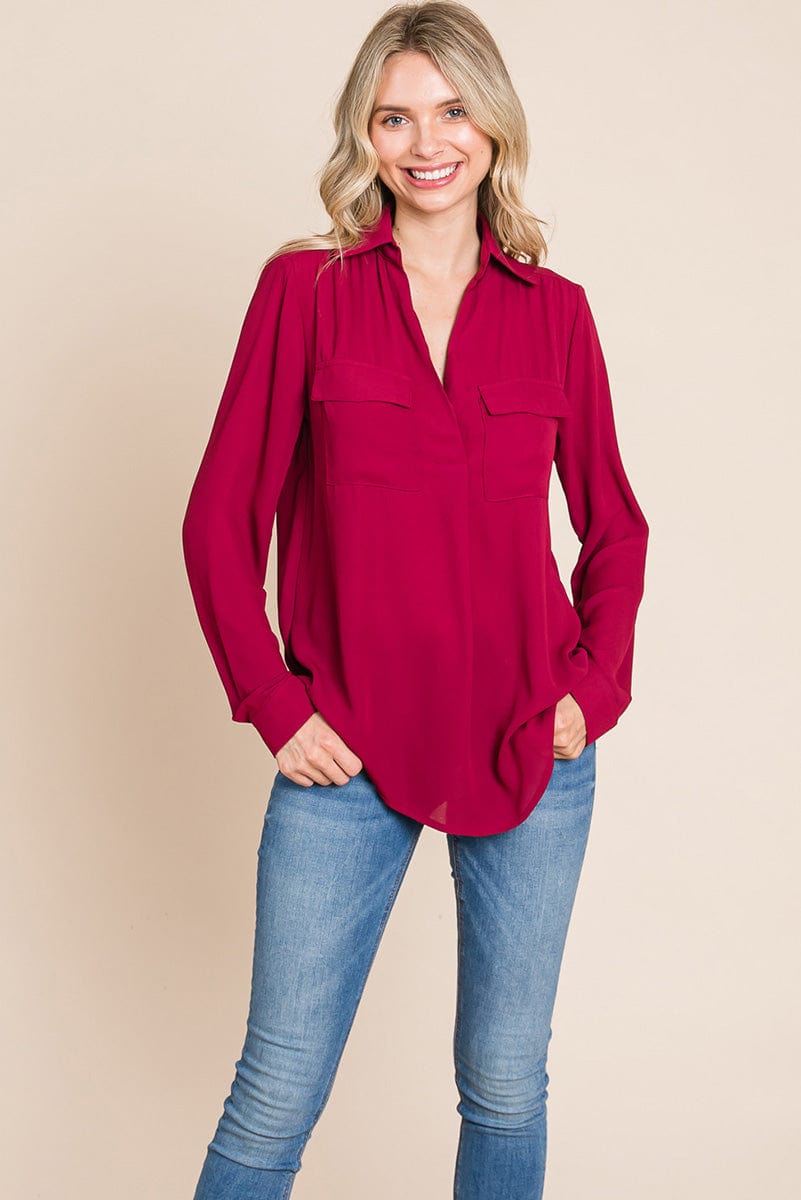 A stylish V neck collared blouse with two front pockets, featuring long sleeves and a button front, displayed on a mannequin.