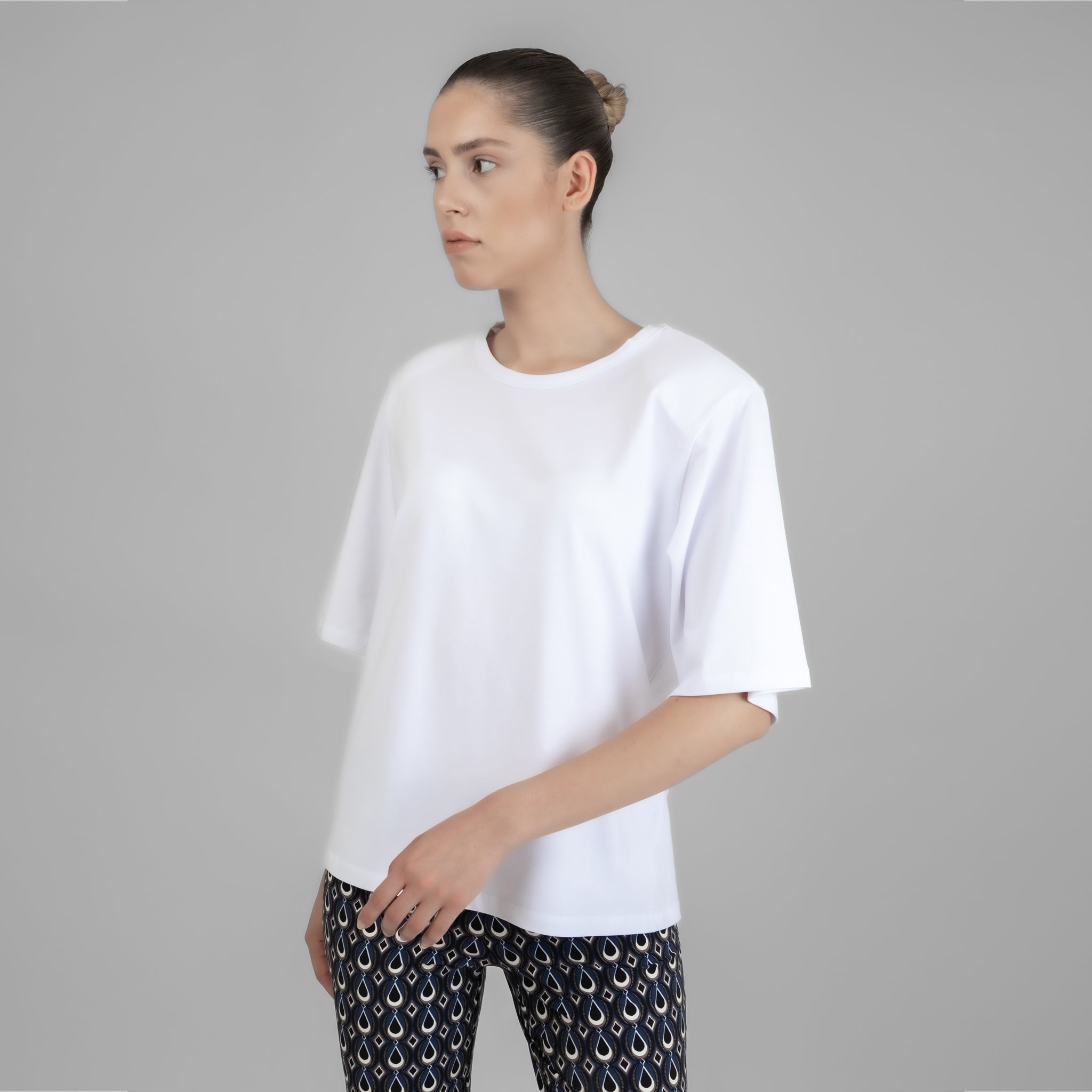 A stylish white shoulder pad tee, Vatkalı Kısa Kollu Beyaz Lucy Basic, displayed on a model, showcasing its elegant design and soft fabric.