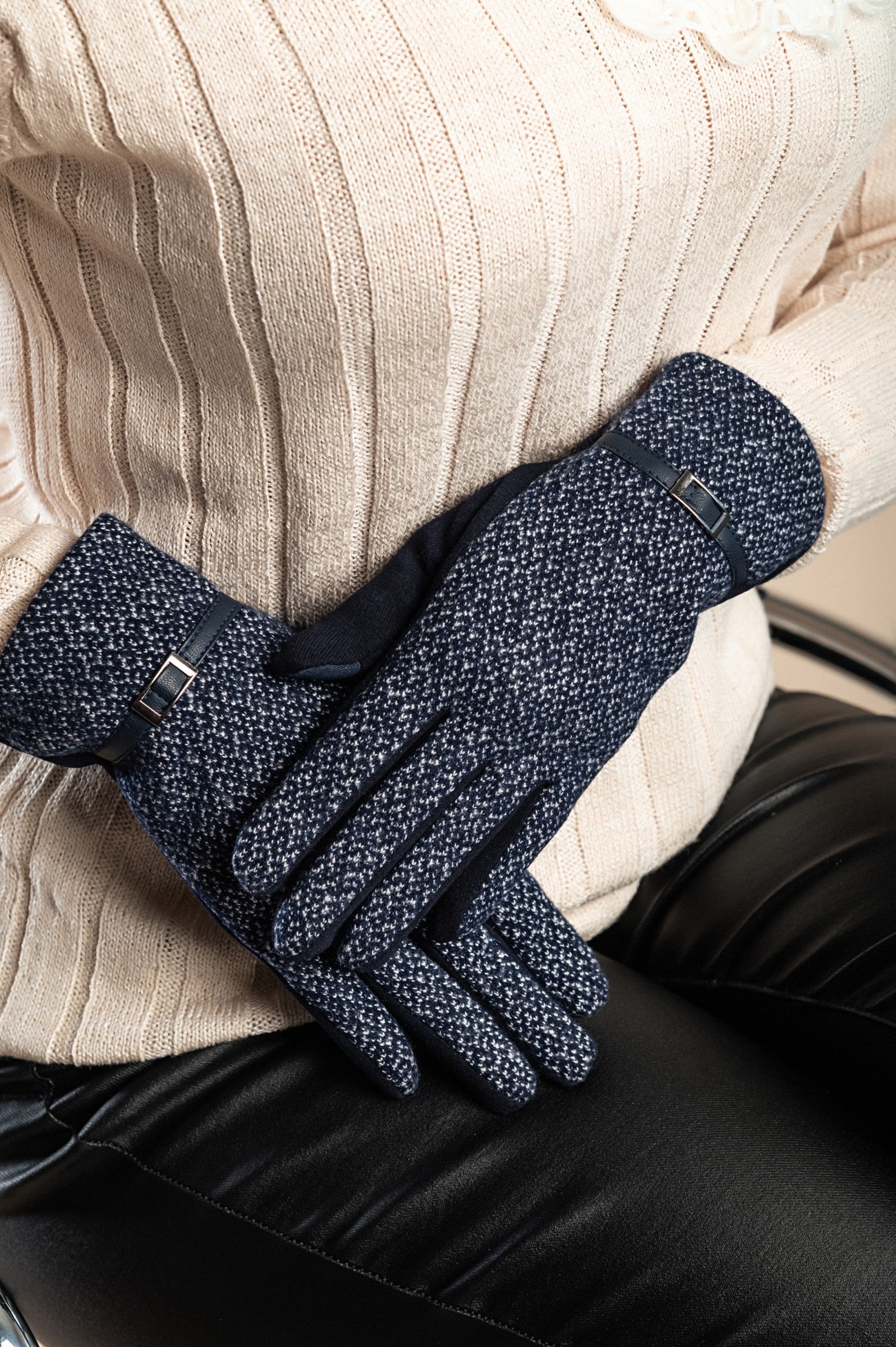 A pair of dark blue warm gloves with a decorative strap on the wrist, showcasing their soft and padded design.