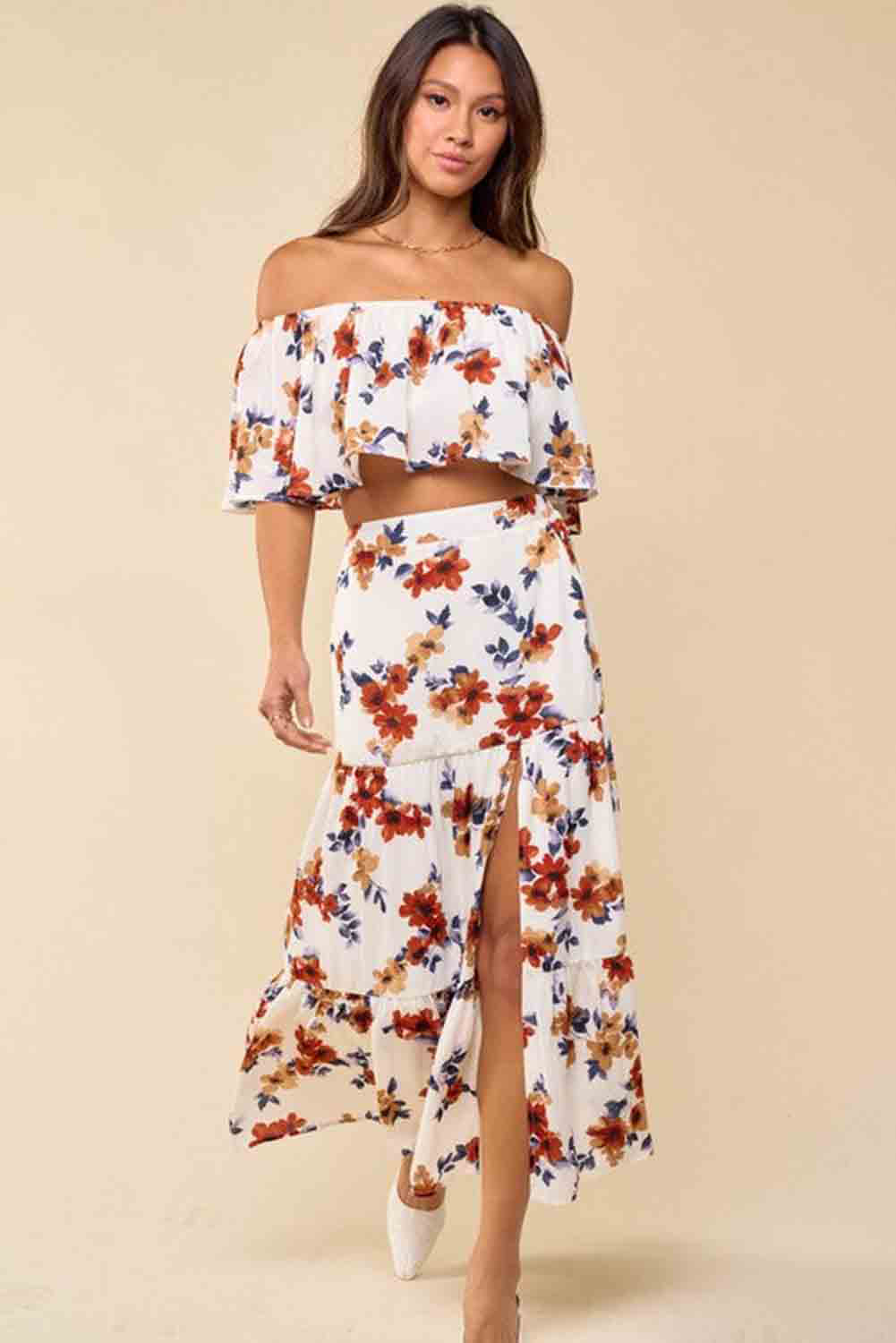 A stylish white floral print off-shoulder crop top paired with a flowing maxi skirt featuring a high slit, perfect for summer outings.