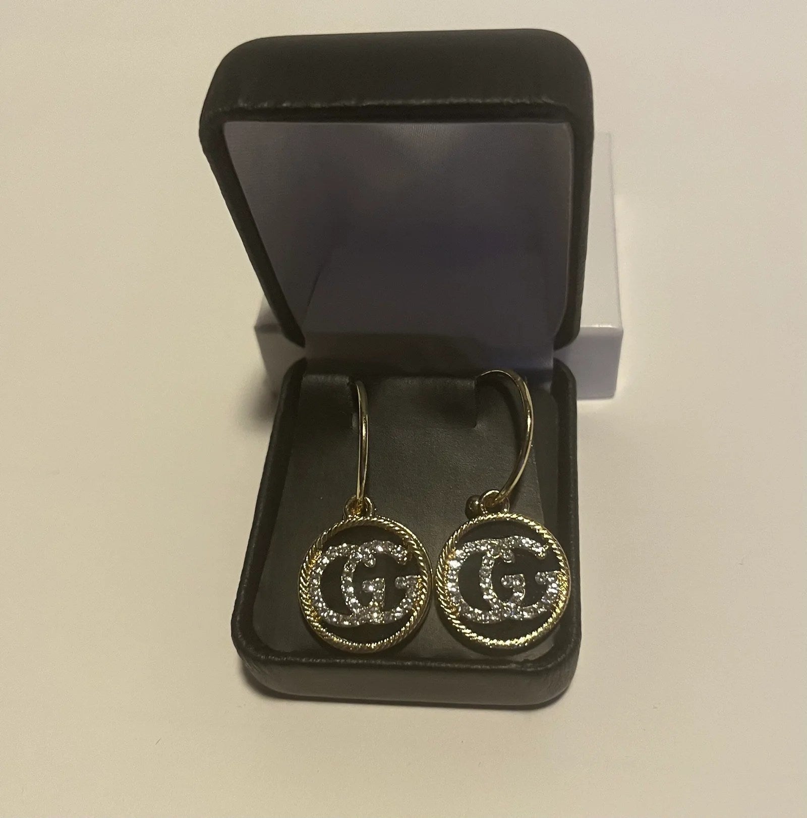 A pair of elegant Women Lux Earrings featuring a gold and black design, crafted from genuine leather, showcasing a luxurious pendant style.